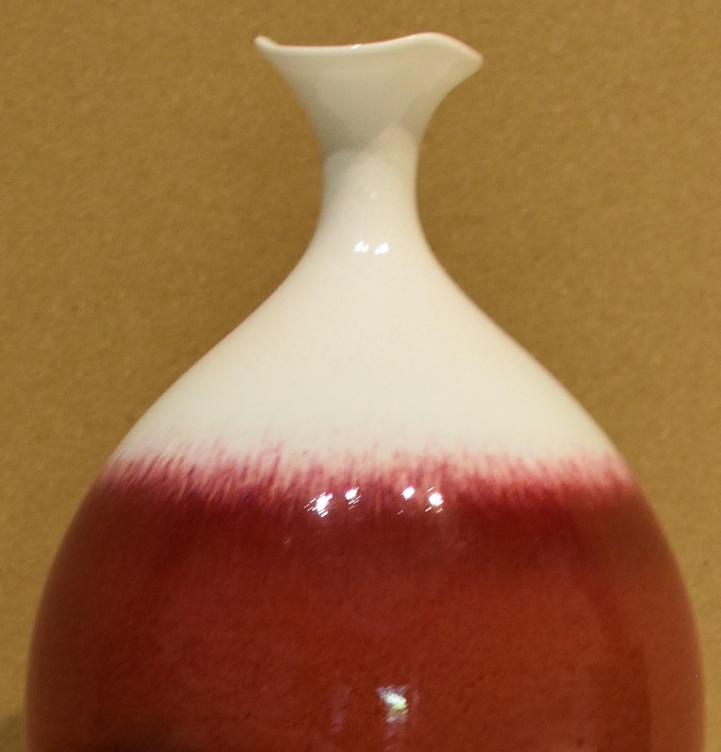 Exquisite hand-glazed Japanese contemporary decorative porcelain vase in an elegant shape in deep red and white, by a master porcelain artist of the Arita-Imari region of Japan.
The artist’s basic philosophy is to create a work of art that
