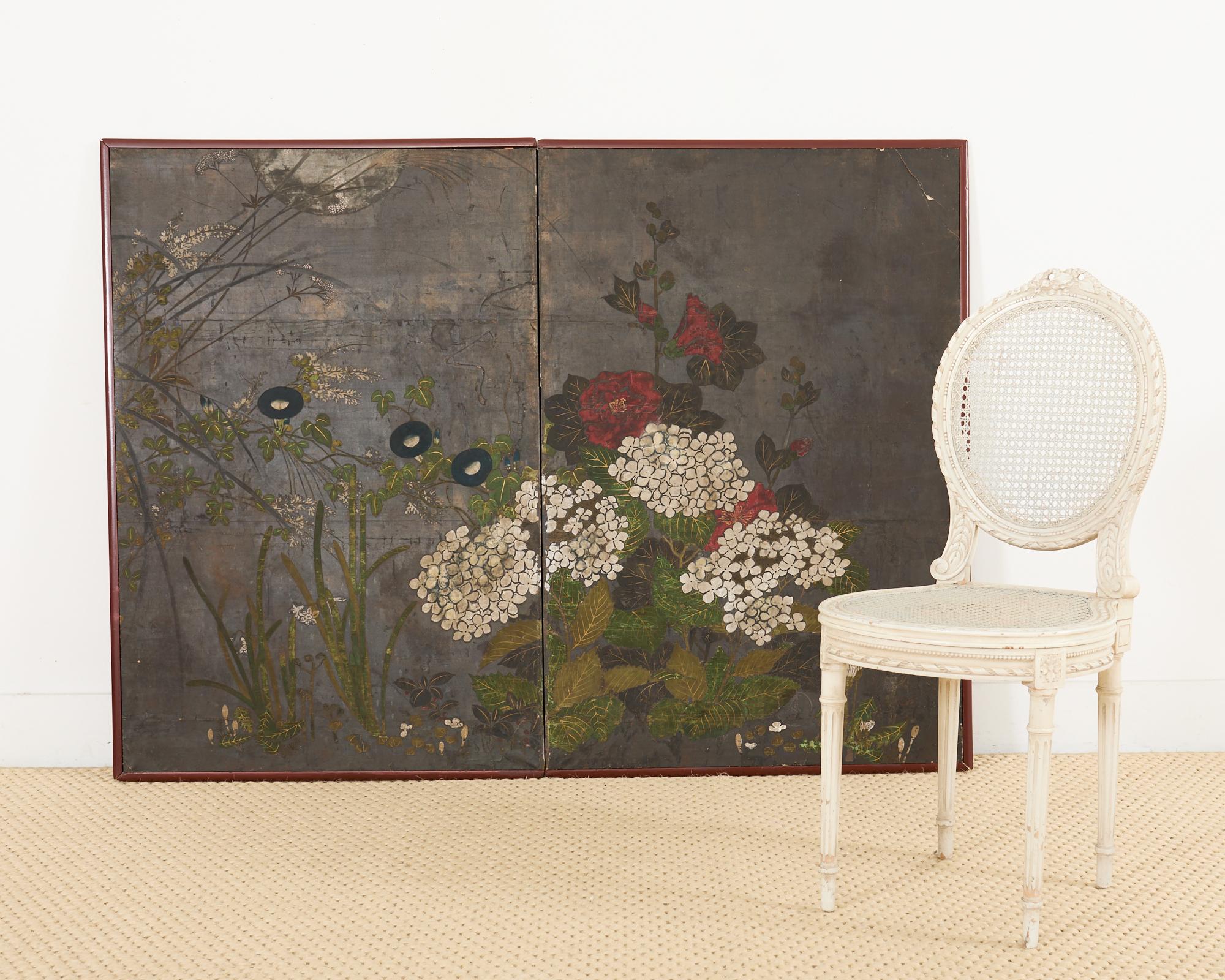 Fascinating 19th century Japanese Edo period two-panel byobu screen featuring a dramatic moonlit landscape with flowering plants and grasses. Painted in the Rimpa school style with ink and natural color pigments over a dark silver leaf background.