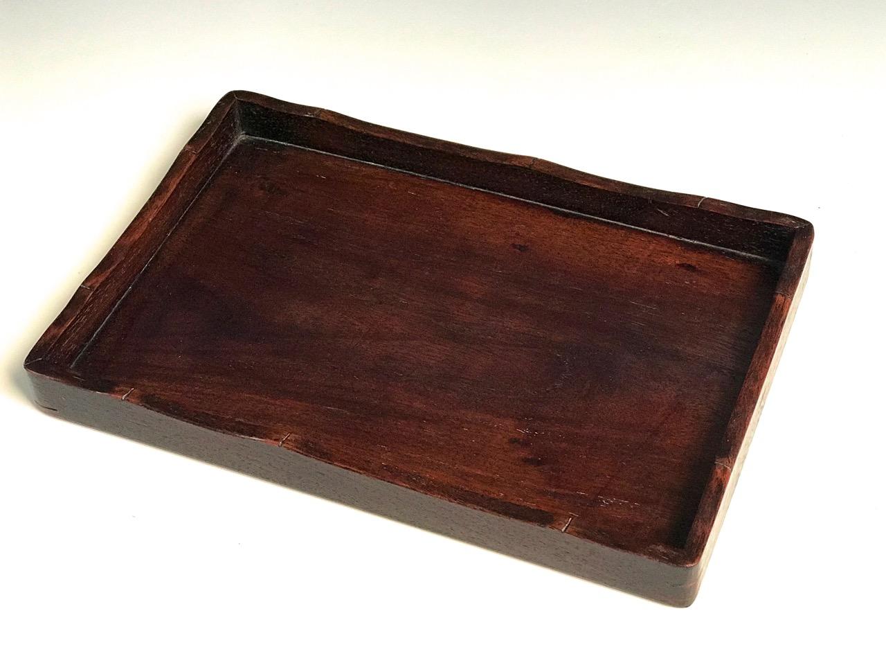 Japanese rosewood tray in the Chinese style, with a center floating panel tongued into the simple rounded corner gallery frame with curved contour detail, resembling the edge of bamboo having mortised joints.
Condition: Signs of wear, otherwise in