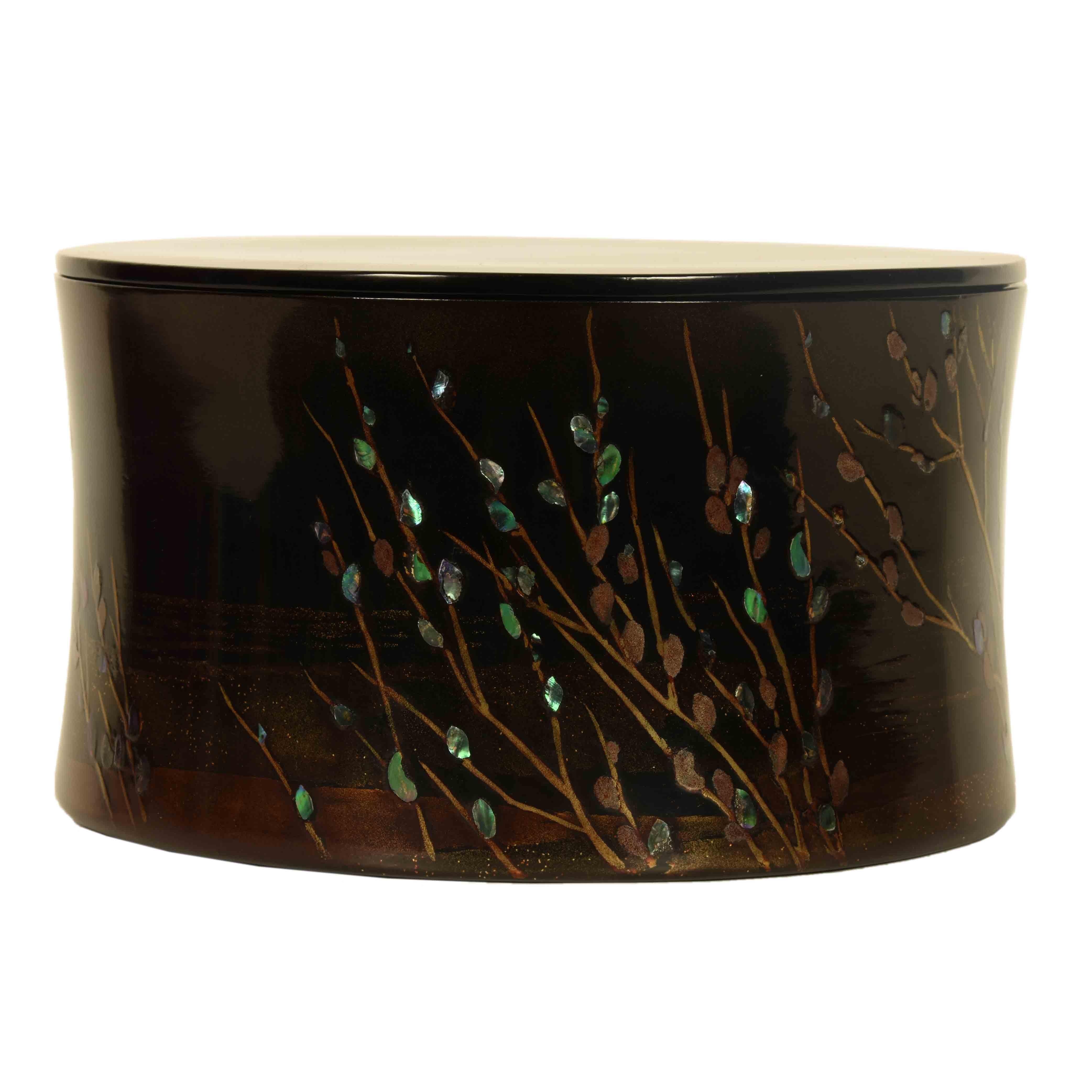 An elegantly decorated round, black lacquer, vintage Japanese box with a simple design of a moon rise over branches in bud, with the branches depicted using a gold maki e technique and each bud, illuminated with an inlay of abalone shell, a