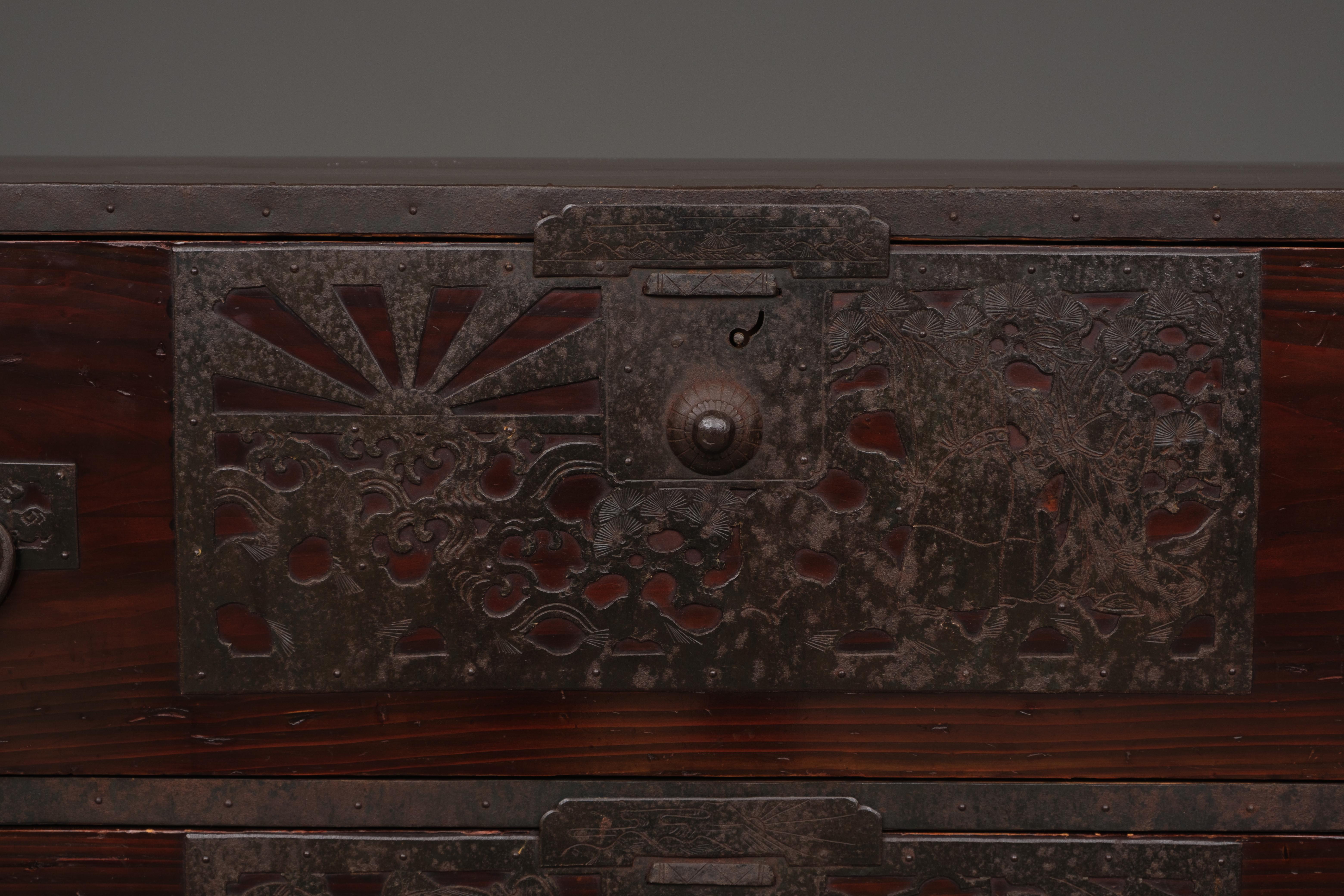 High-quality Sado wooden ishô’dansu (cabinet of drawers) in two sections. Heavily clad with decorative iron hardware featuring rich designs, and a little secret. Fully restored, cleaned and waxed.

The drawer faces made from solid indigenous cedar