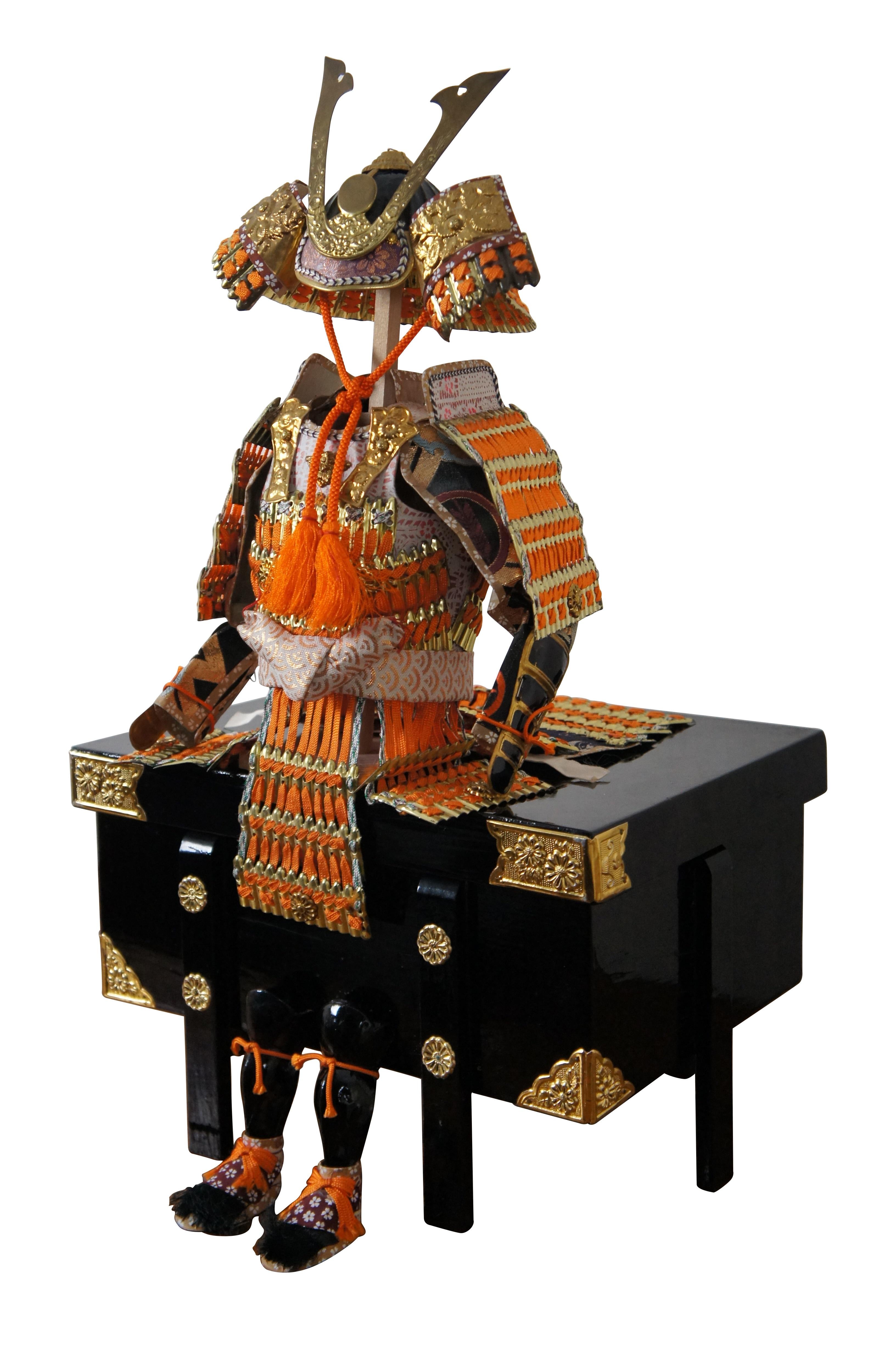 Vintage set of Japanese samurai doll armor in orange and gold, designed to perch on the edge of the black lacquer campaign style storage box with floral gilt metal corner pieces and medallions.

Dimensions:
12.5” x 9.25” x 21.5” (Width x Depth x