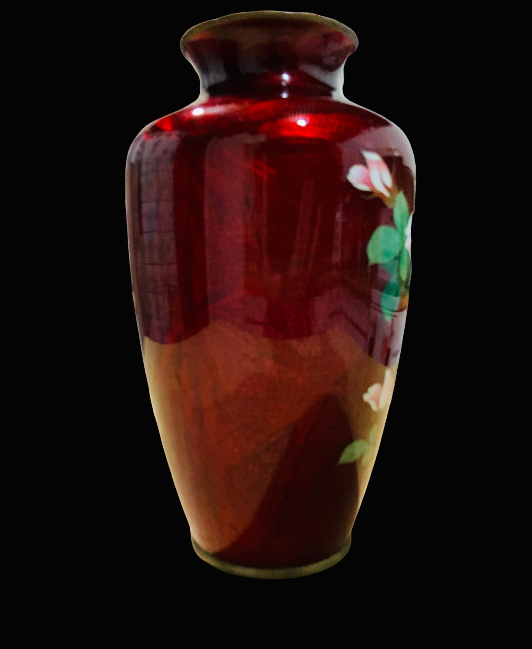 Dies ist eine Cloisonné-Vase aus roter Metallfolie, die einen Strauß großer rosa Rosen und Knospen mit grünen Blättern darstellt. In der roten Folie ist ein Vogel und ein Bambuszweig eingezeichnet.