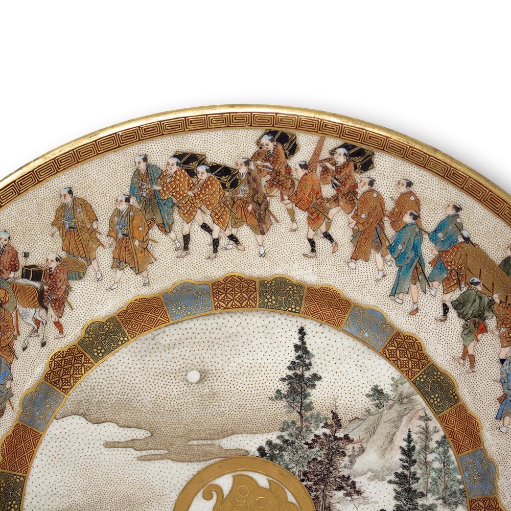 Fine Japanese satsuma plate displaying a daimyo procession. The plate extensively decorated with an outer boarder of gilt greek key upon a red base surrounding a Japanese procession of the highest order featuring an army of figures in a continuous