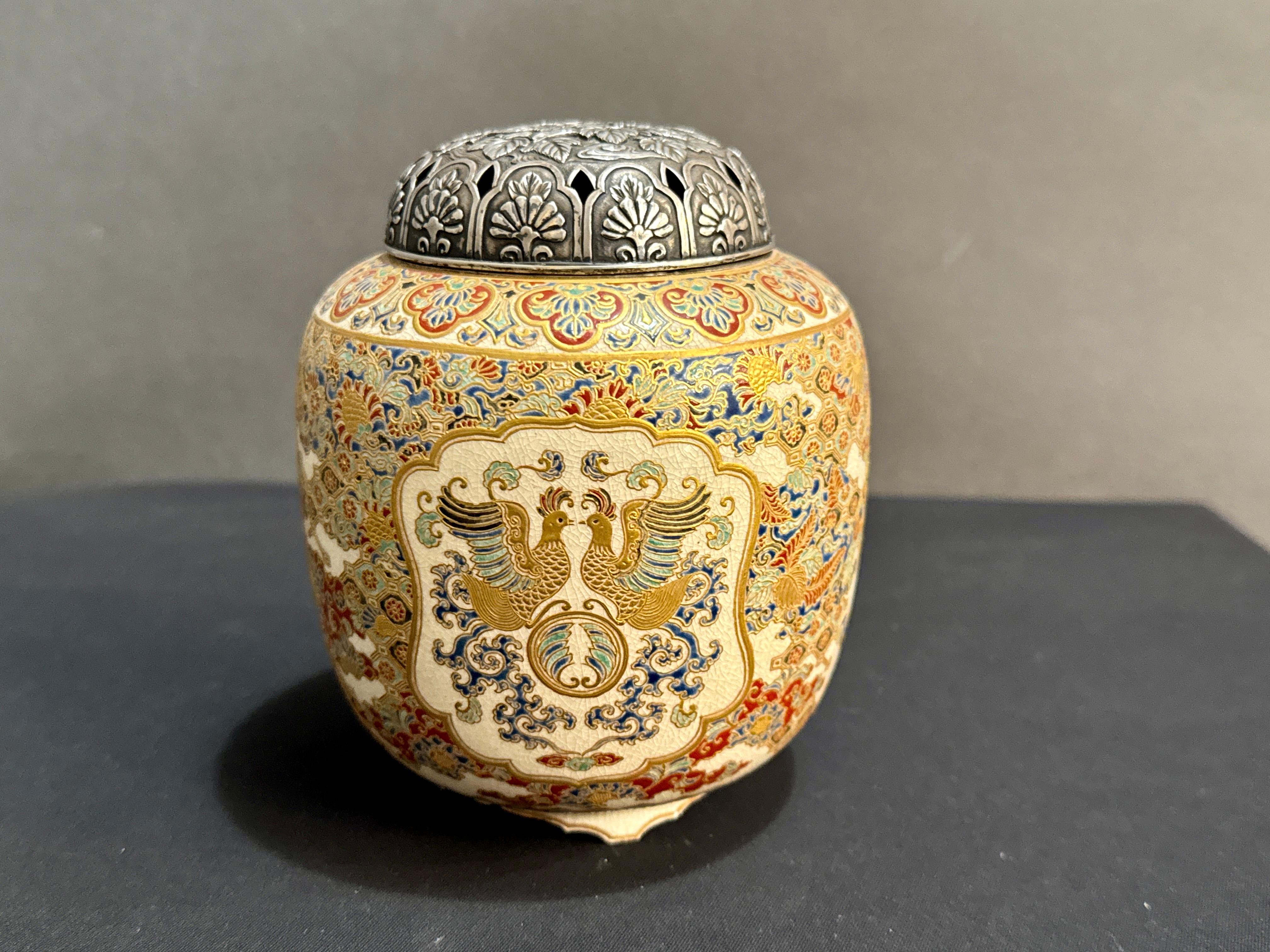 A fantastic Japanese Satsuma incense burner, koro, with phoenix and brocade designs and a silver lid, Meiji Period, late 19th century, Japan.

The censer, called a koro in Japan, of generous barrel form, and set on a recessed foot raised on three