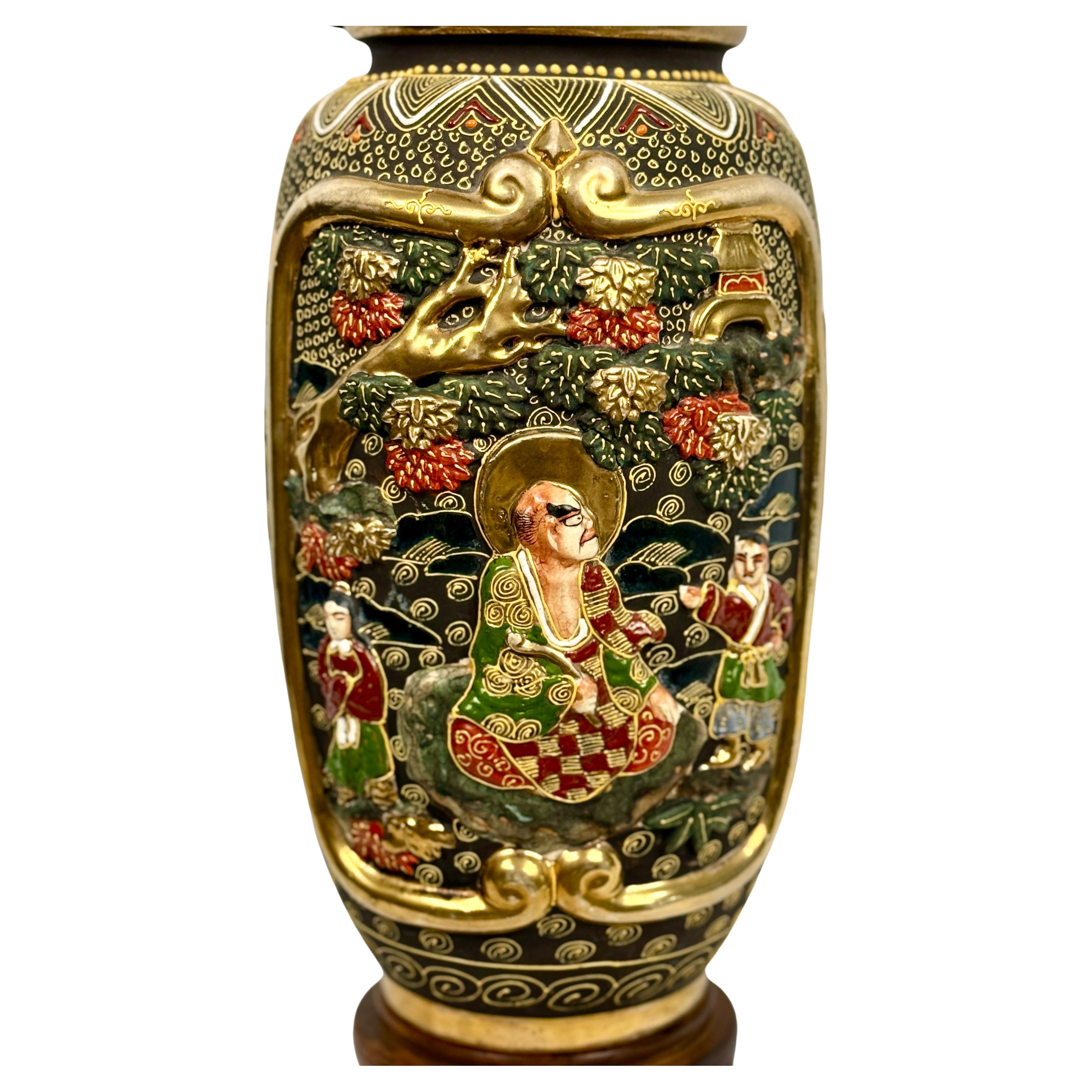 Mid-20th Century Japanese Style Porcelain Table Lamp inspired by the Satsuma style of ceramics which originated in Japan during the late 19th and 20th centuries. Lamp features rich colors of green, red and gold on a black background with gilt trim.