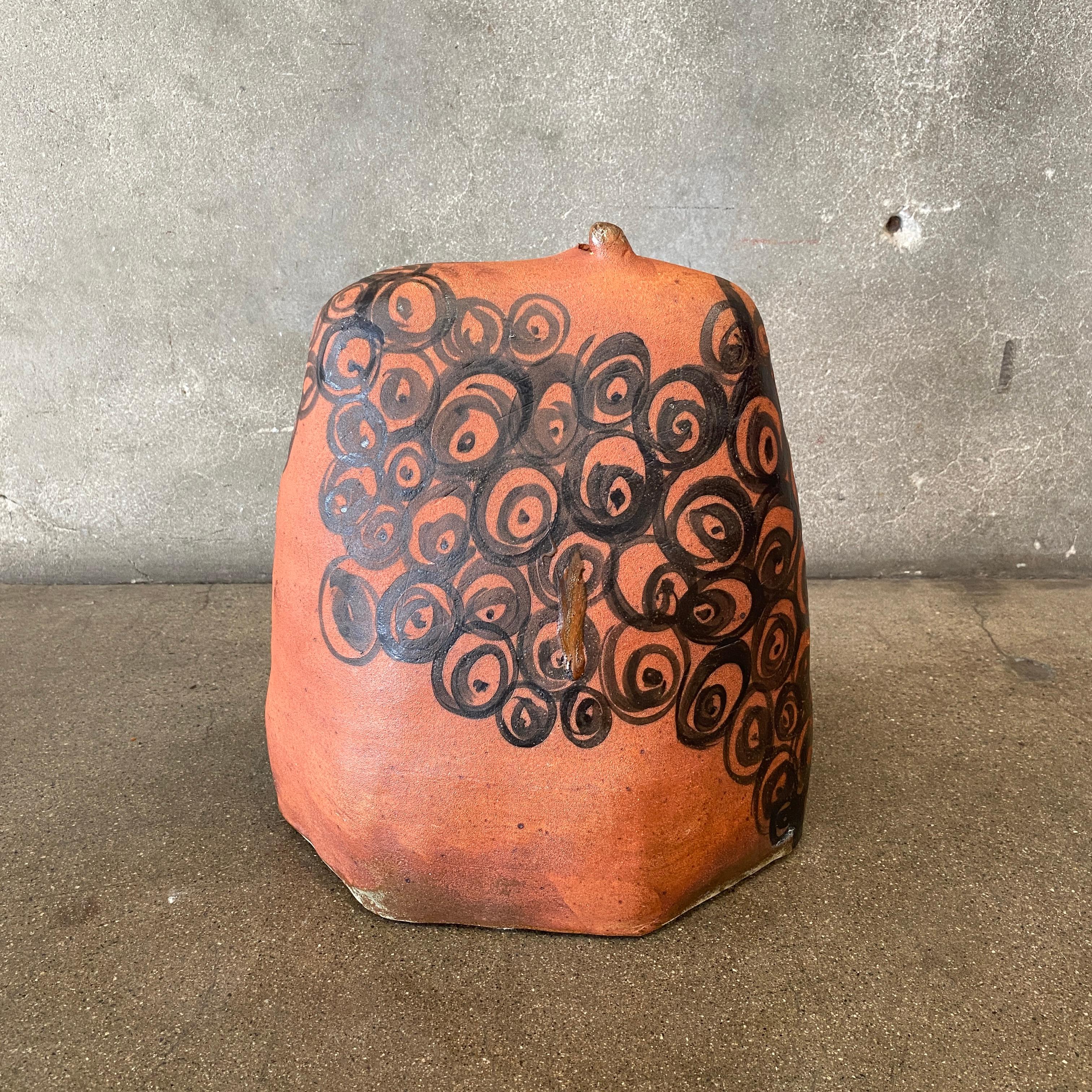 This is a large handmade Japanese sculptural vase with stunning spirals handpainted with a black glaze on top of a terracotta-colored red ceramic clay. The base of the vase is signed by Susan Mollet. The little pop-up hole on the top allows the