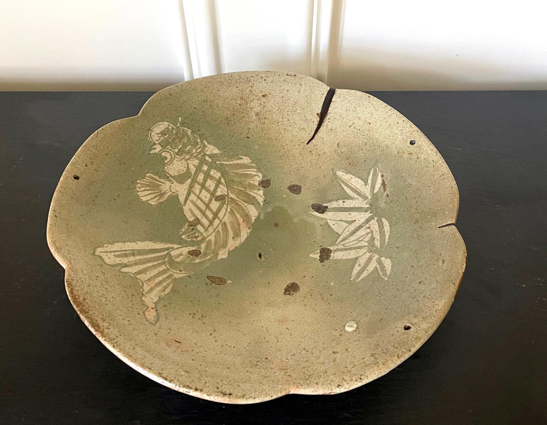 A glazed stoneware Ishizara (food serving platter) from Seto kilns. The platter features an unusual lobed edge and a slight irregular form from hand made. On the plate, a carp and a bamboo branch were highlighted in a green-celadon glaze, with an