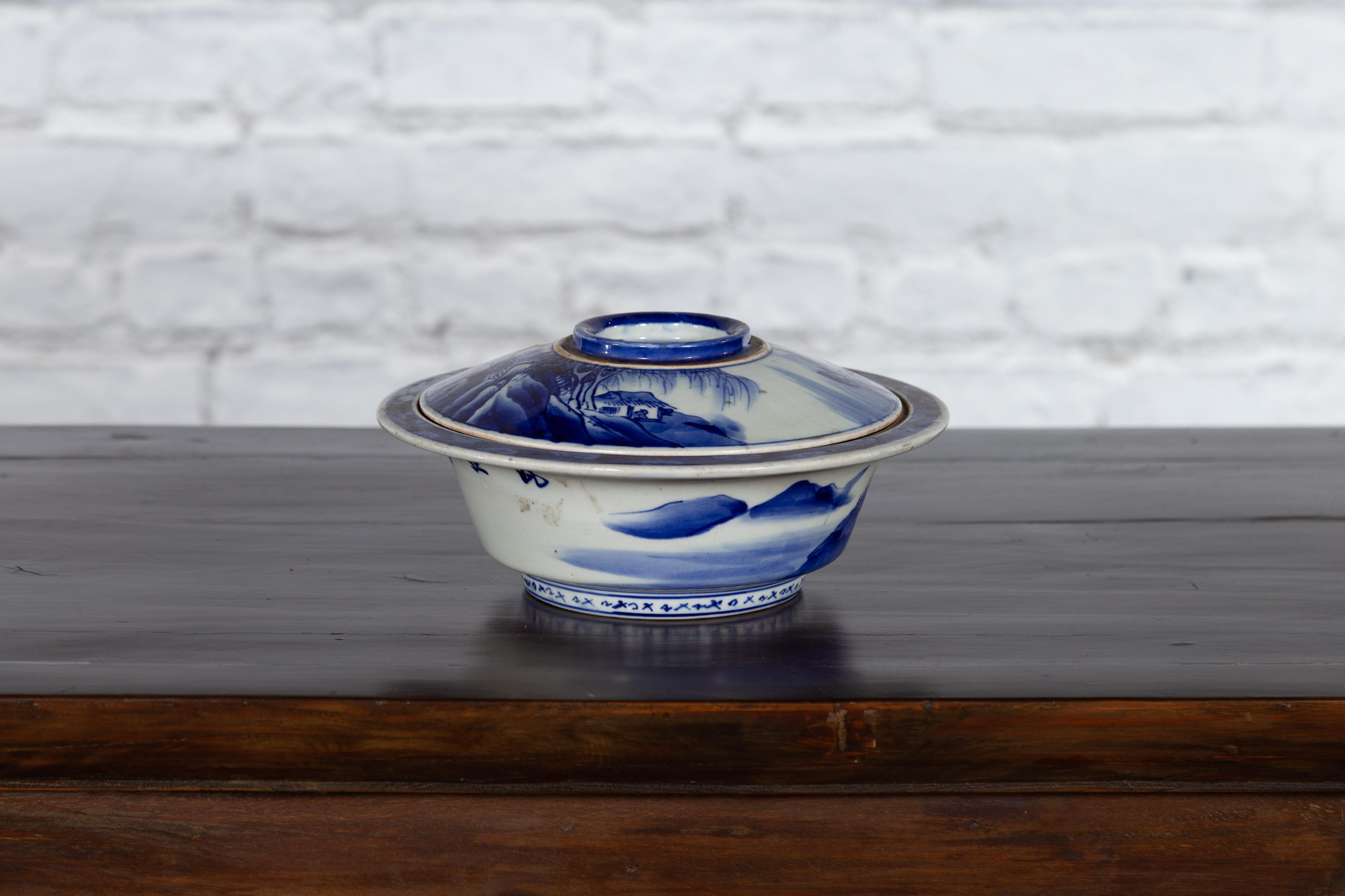An antique Japanese blue and white hand-painted porcelain Seto ware vegetable bowl from the early 20th century, with landscape and calligraphy décor. Produced in one of the six ancient kilns of Japan, this porcelain vegetable bowl features a