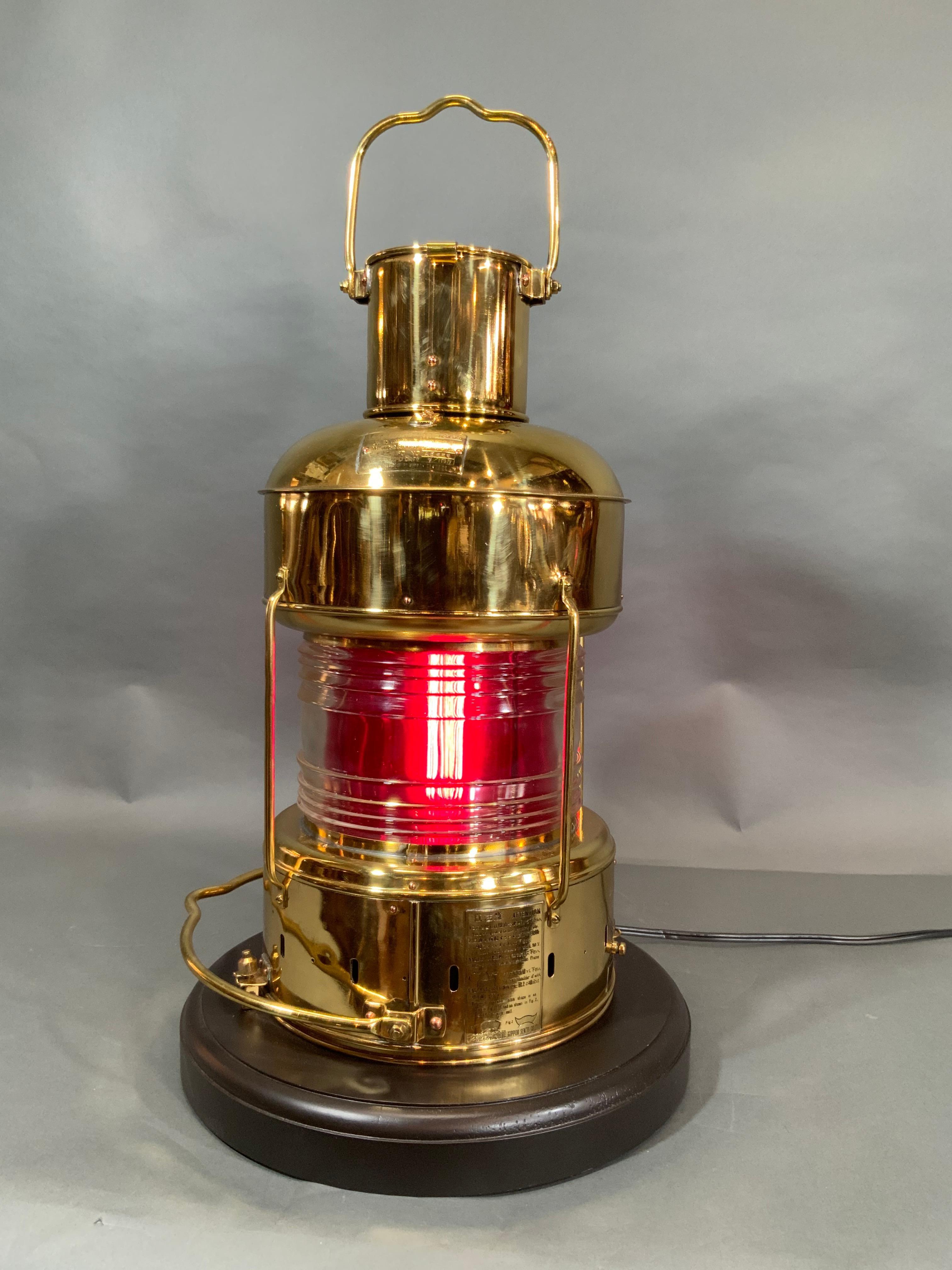 Genuine solid brass ship's lantern by Japanese maker Nippon Sento Co. LTD. Clear Fresnel glass lens with removable red filter. Mid twentieth century anchor lantern that has been meticulously polished and lacquered to an incredible level, then wired