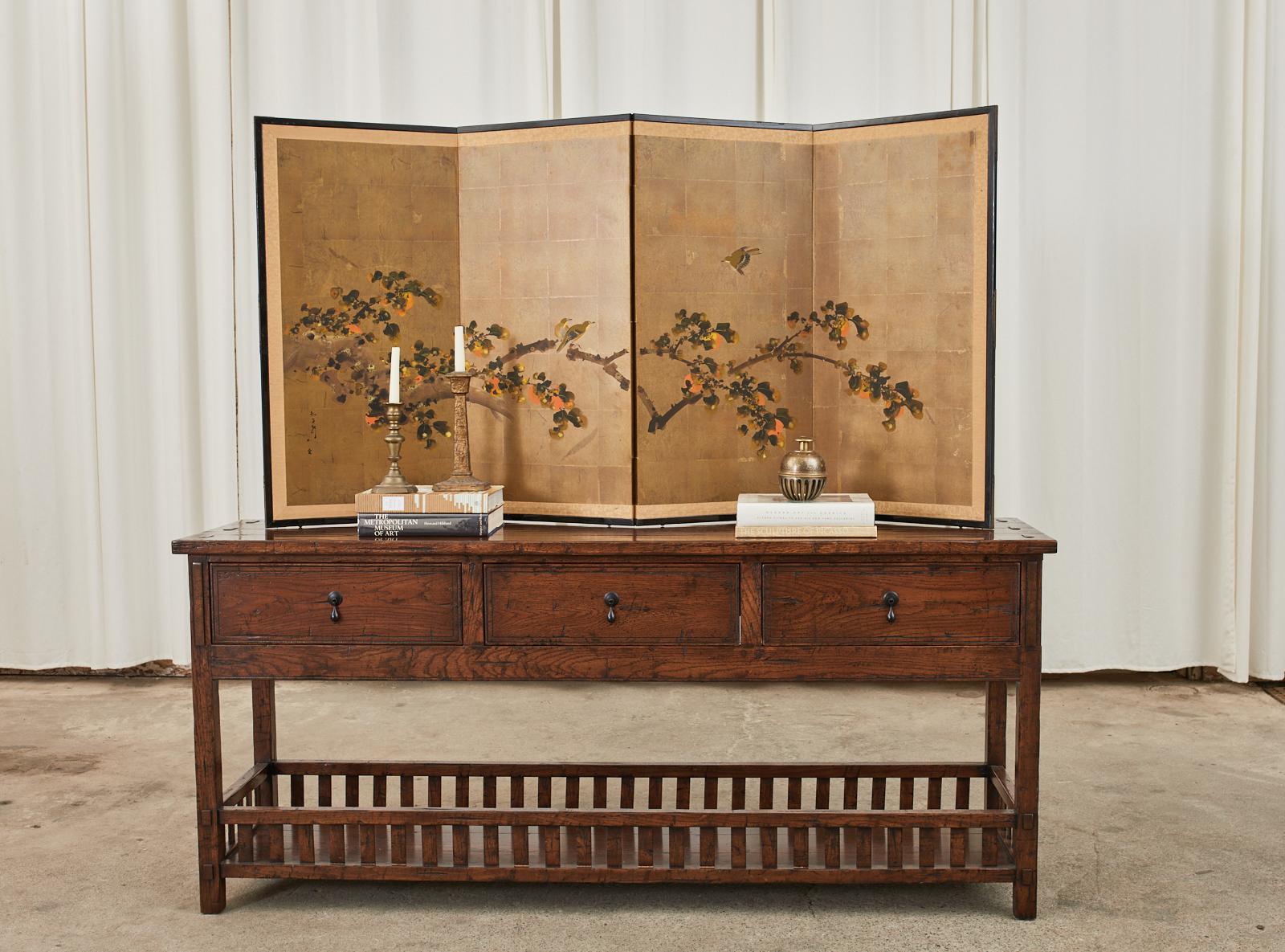 Delightful Japanese Showa period four-panel byobu screen depicting a fruiting persimmon tree with sparrows over a gilt background. Ink and color pigments painted in the Nihonga school style. Signed by artist on left bottom side. Set in a black