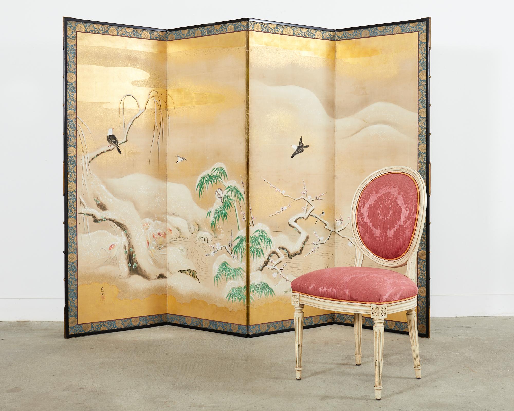 Impressive large scale Japanese Showa period four panel byobu screen depicting a serene snowy winter landscape with willow, prunus, and bamboo. The screen features an amazing background of gold leaf clouds and gold leaf specks. Vibrant ink and
