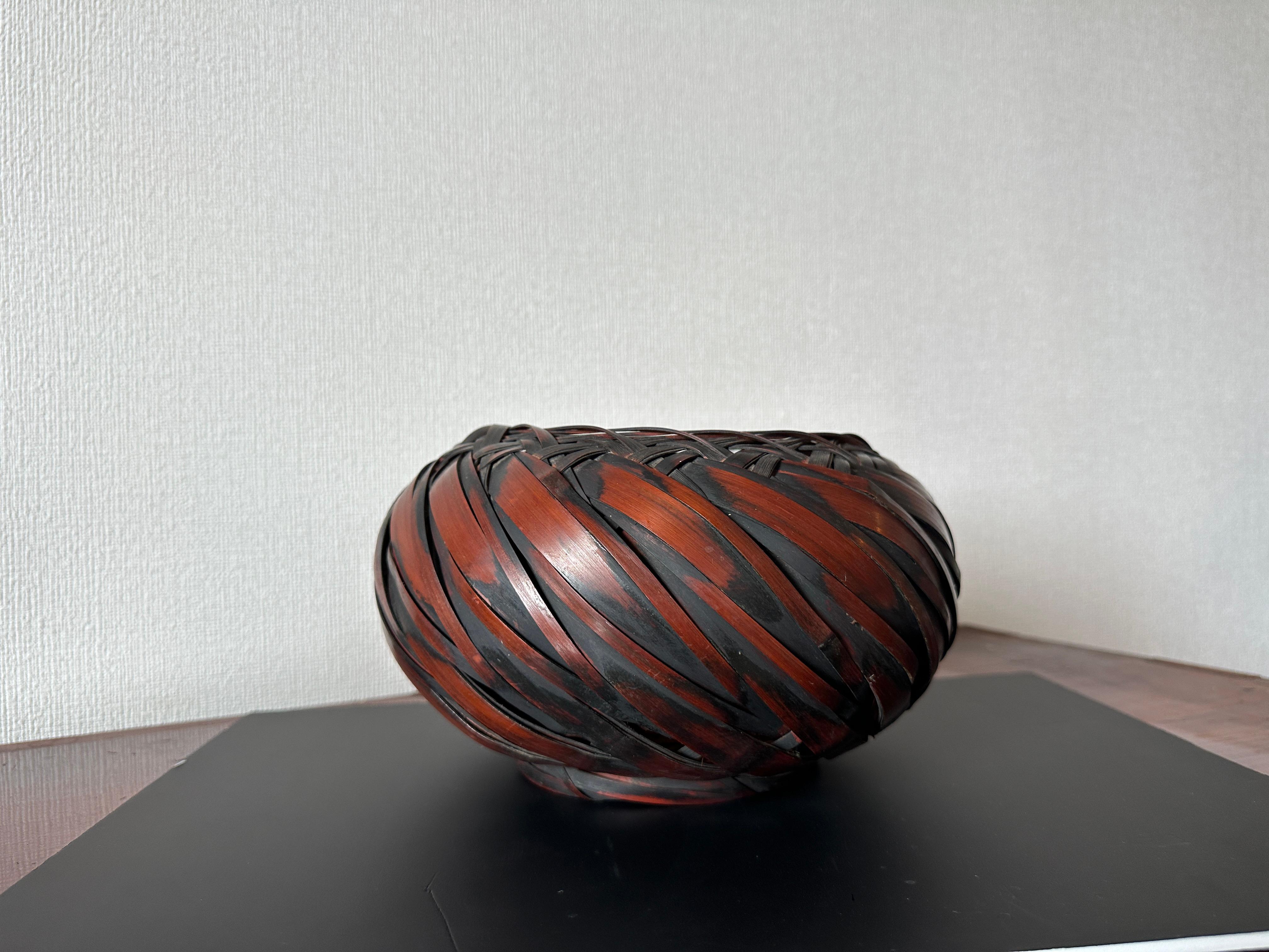Panier à fleurs en bambou torsadé de la période japonaise Showa
Dimensions : H 16 cm × L 23 cm × P 23 cm

Ce panier sculptural en bambou japonais présente un tressage dynamique en spirale, avec de larges bandes de bambou fendues et étroitement