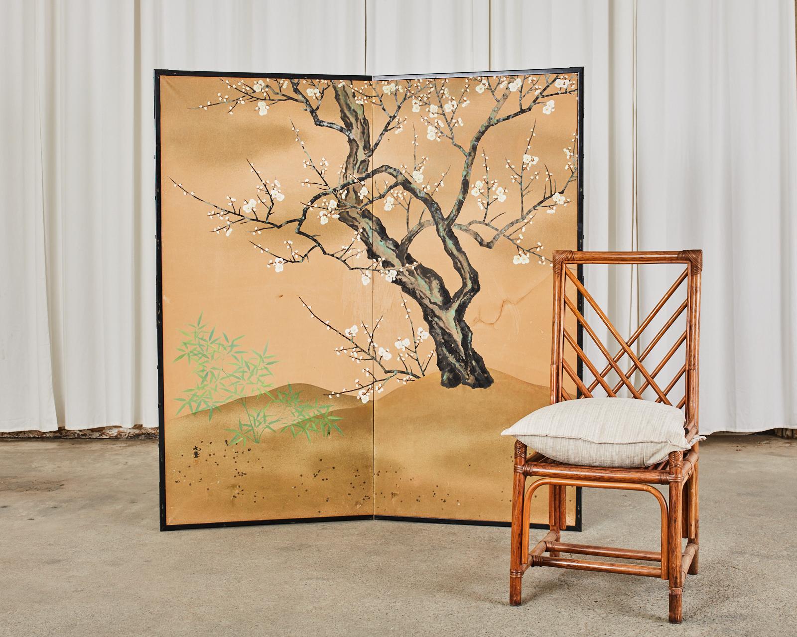 Serene Japanese Showa period two-panel folding byobu screen depicting a large spring blossoming prunus tree or plum tree. Beautifully painted with ink and natural color pigments on mulberry paper and subtle gold flecks signed by artist Ganko and