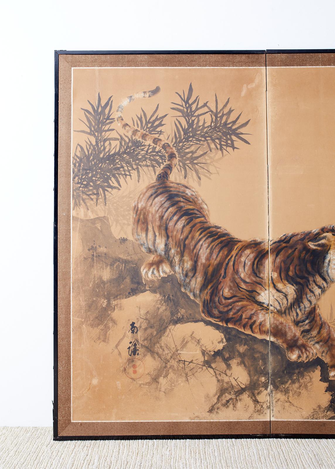 Captivating Japanese Showa period two-panel screen depicting a fierce tiger in bamboo. Painted in the Nihonga School style signed Nankei with an artist seal on the left side. Ink and color pigments on handcrafted paper. Set in a black lacquered