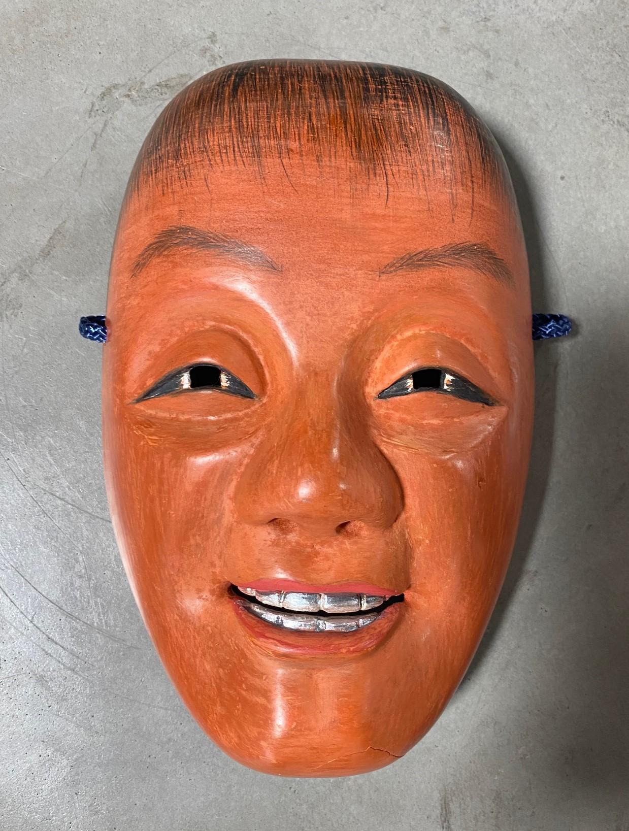 A beautiful, wonderfully crafted, alluring mask made for Japanese Noh theatre.

The mask is handcrafted and hand carved from natural wood and is signed by the maker. 

This mask is of the often drunk, youthful red-faced sprite fairy character