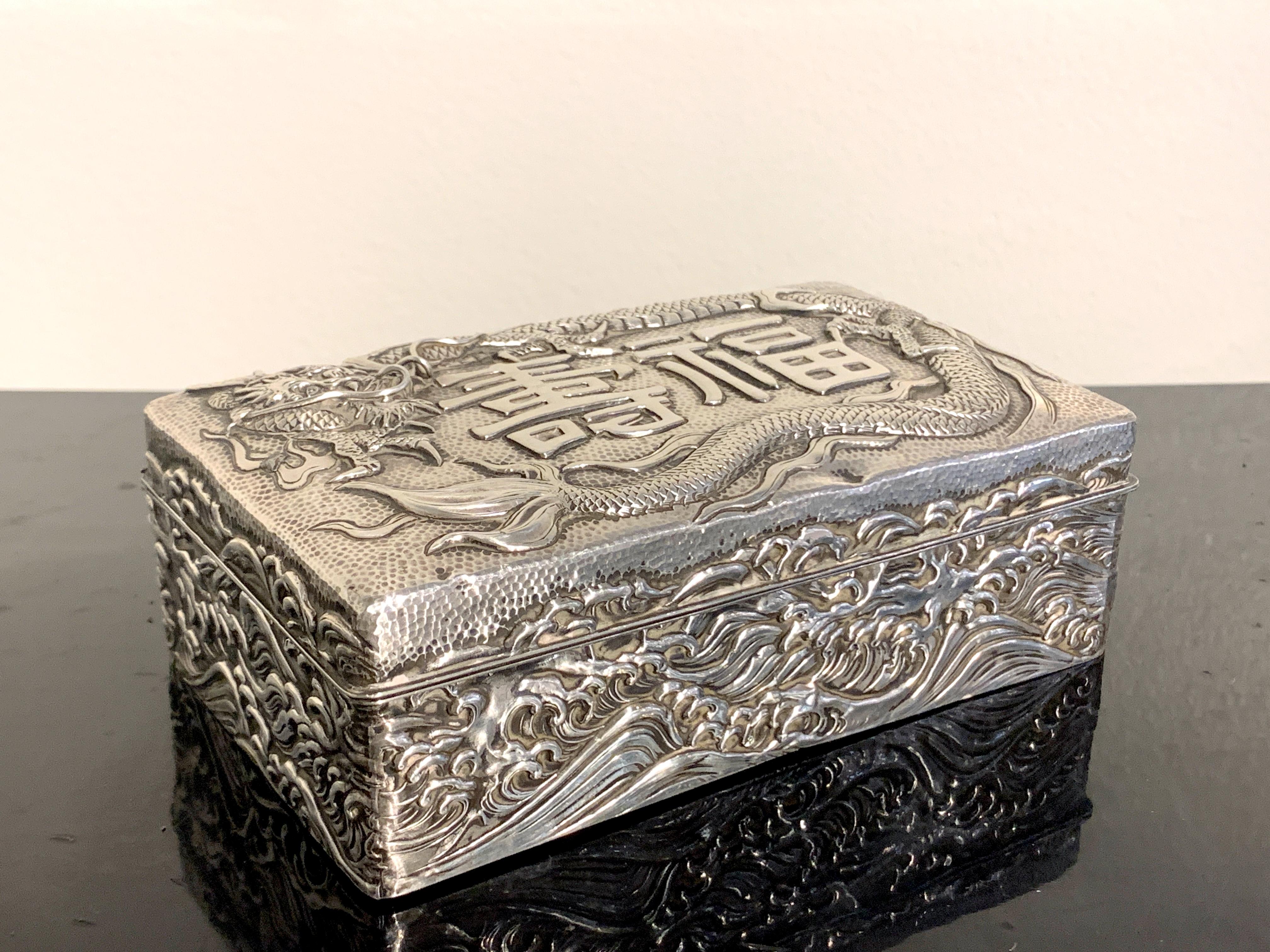 A Japanese hardwood box clad in repoussé silver with a design of the Japanese characters 