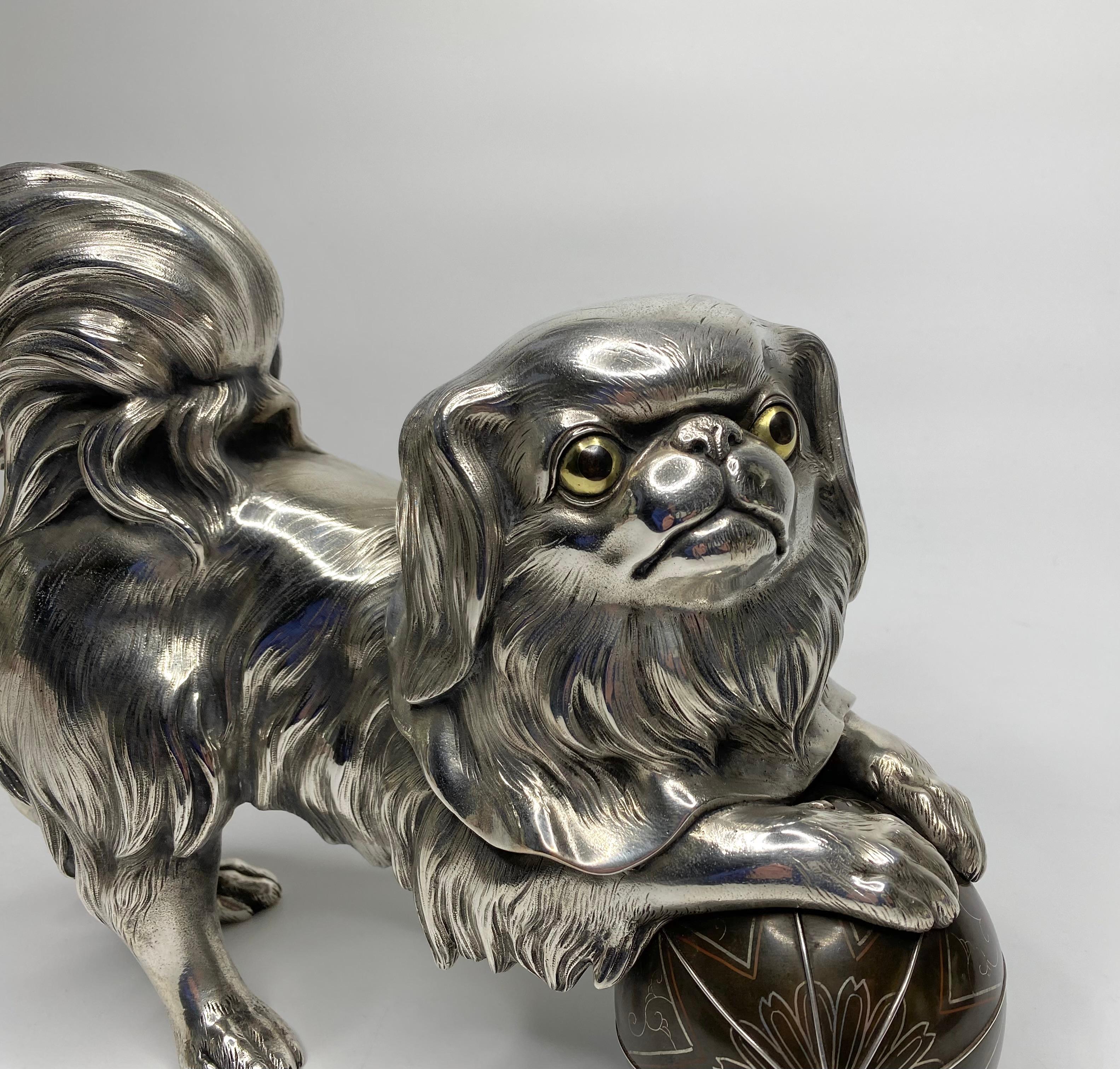 Silvered bronze okimono of a Chin puppy, Japan, Meiji Period.

£8,900.00
A large, and heavy Japanese silvered bronze okimono, c. 1890, Meiji Period. Finely modelled as a Japanese Chin puppy, with his paws resting upon a ball.
The playful dog