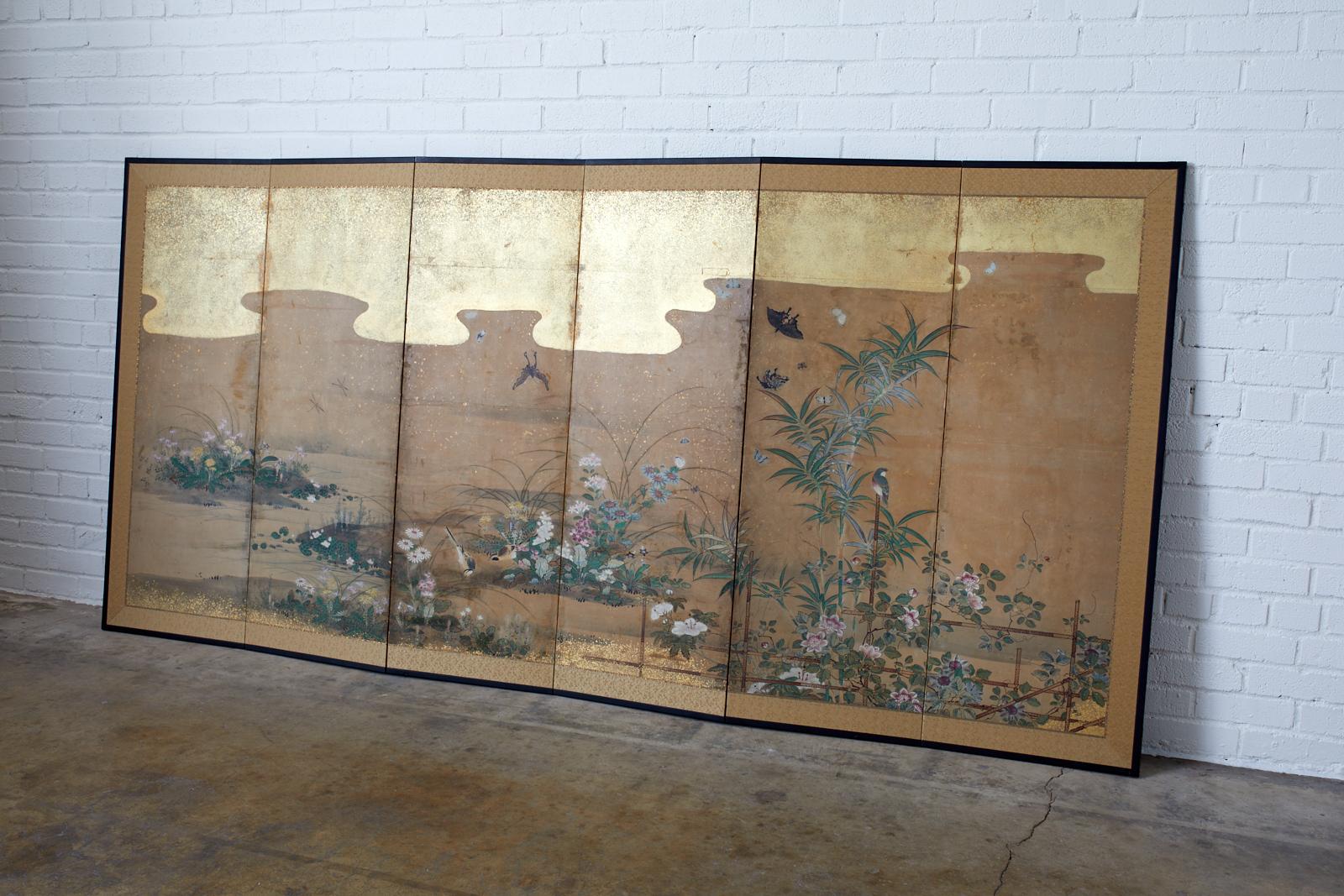 18th century Japanese six panel Edo period screen depicting flora and fauna landscape. Beautifully painted flowers with birds, insects, and butterflies at a water's edge. Ink and color pigments painted in the Kano school style with later added gold