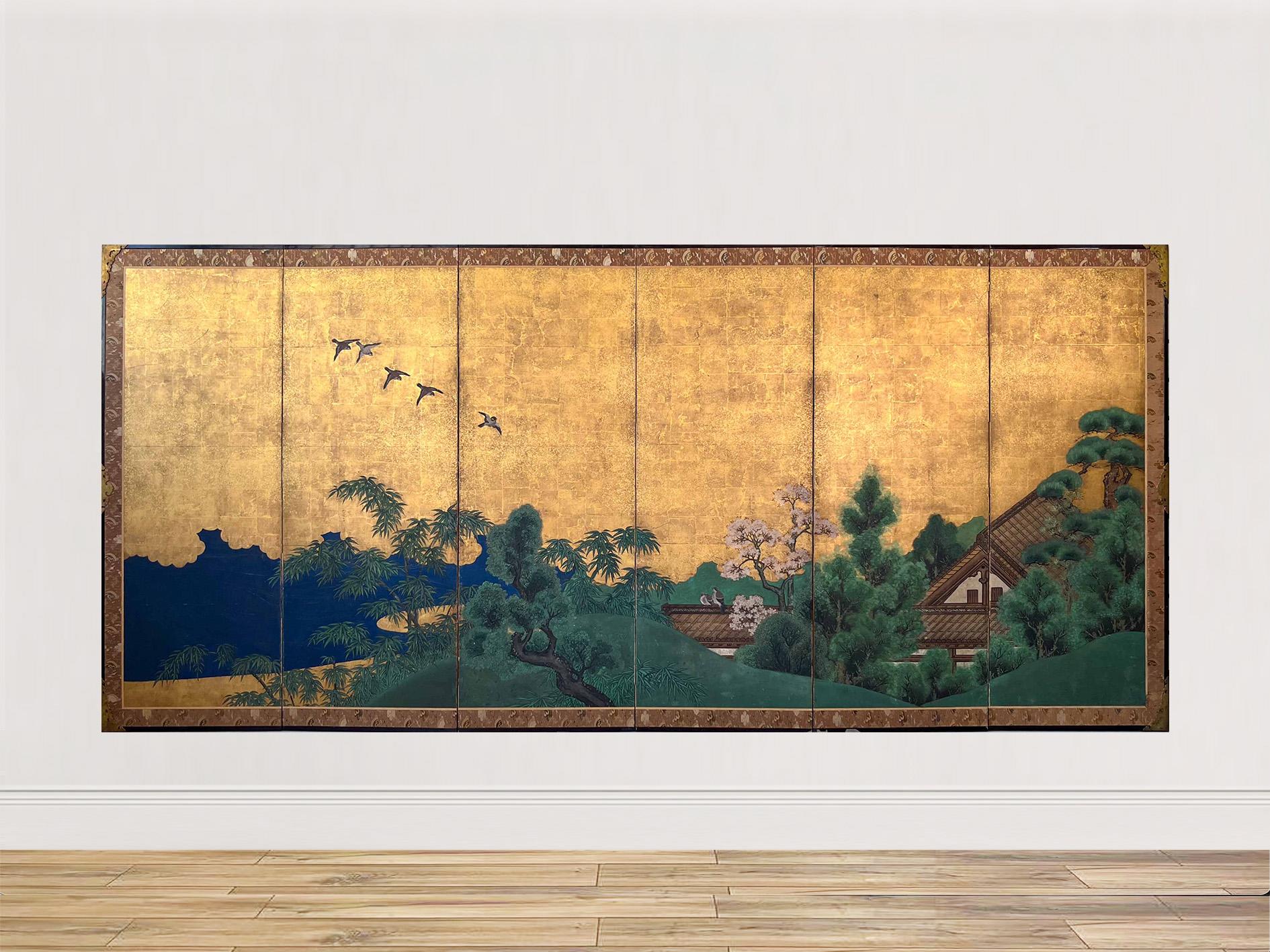 A Japanese six-panel folding screen, decorated with gold leaf and gold powder, depicting a landscape with traditional houses nestled among green hills, streams, and bamboo and pine trees.

At the center stands a blossoming cherry tree, beneath which