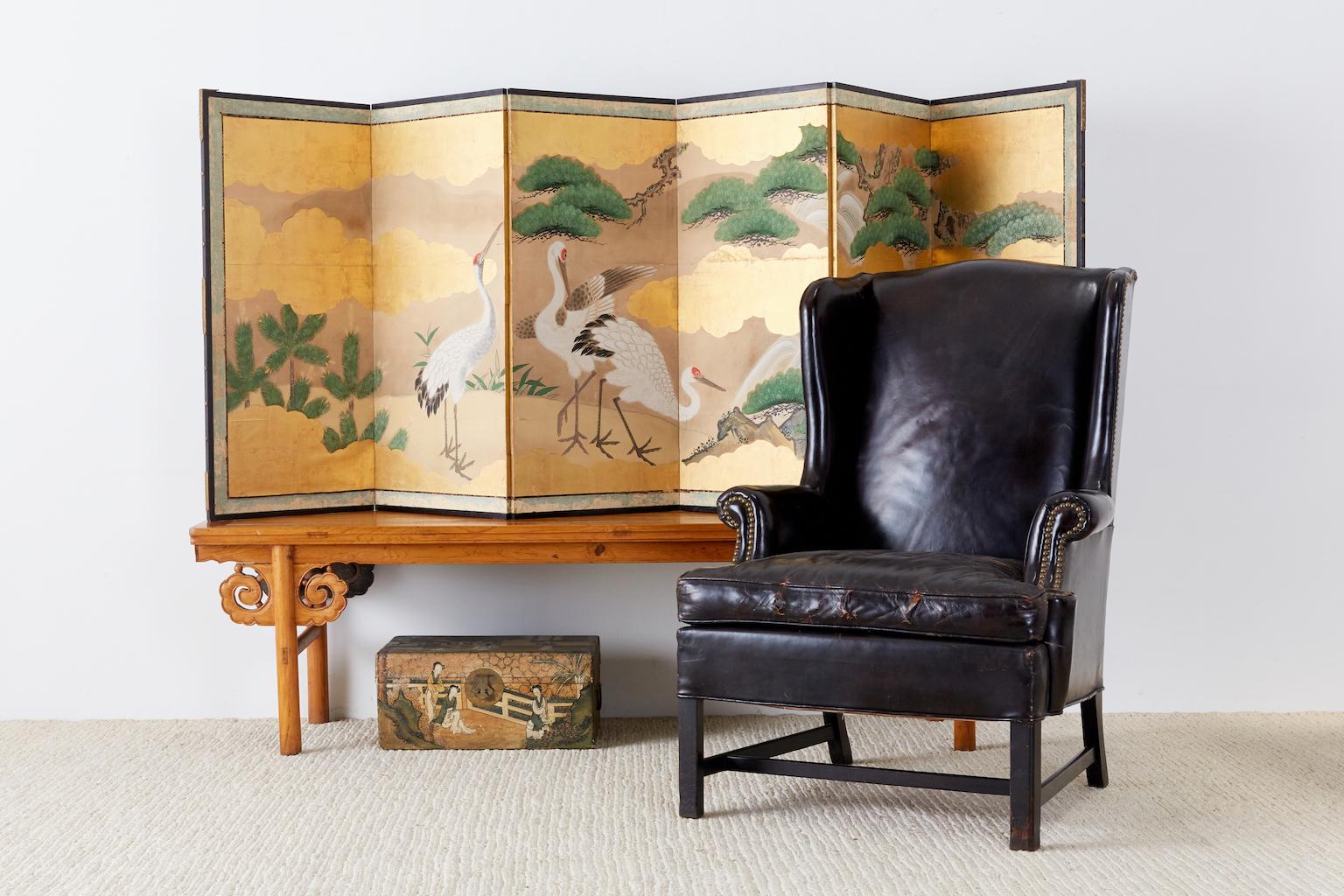 Stunning Japanese six-panel Meiji period screen depicting red crowned cranes in a landscape with pine trees and camellia. 19th century Kano school featuring gold leaf and vivid colored pigments. Shows beautifully with an aged patina and losses on