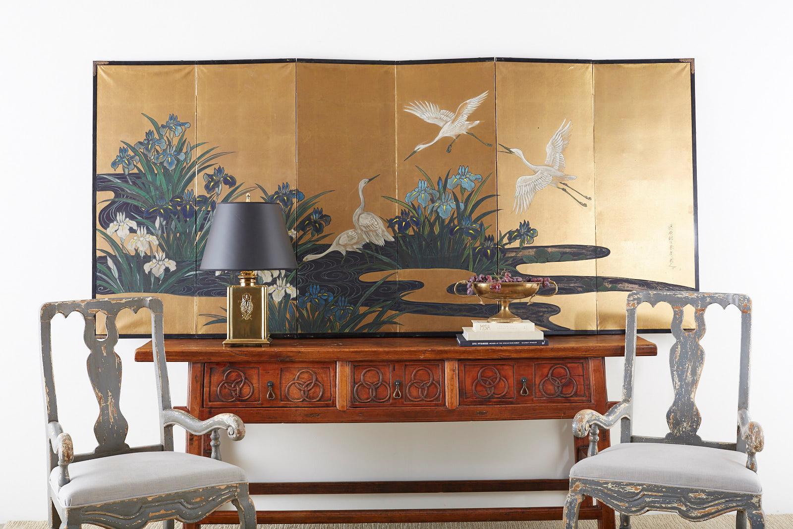 Captivating Japanese six-panel late Meiji/early Taisho Showa period screen featuring five egrets or herons in a water landscape. Painted with vibrant colored pigments over gold leaf squares with a rich, aged patina. The painting is signed on the