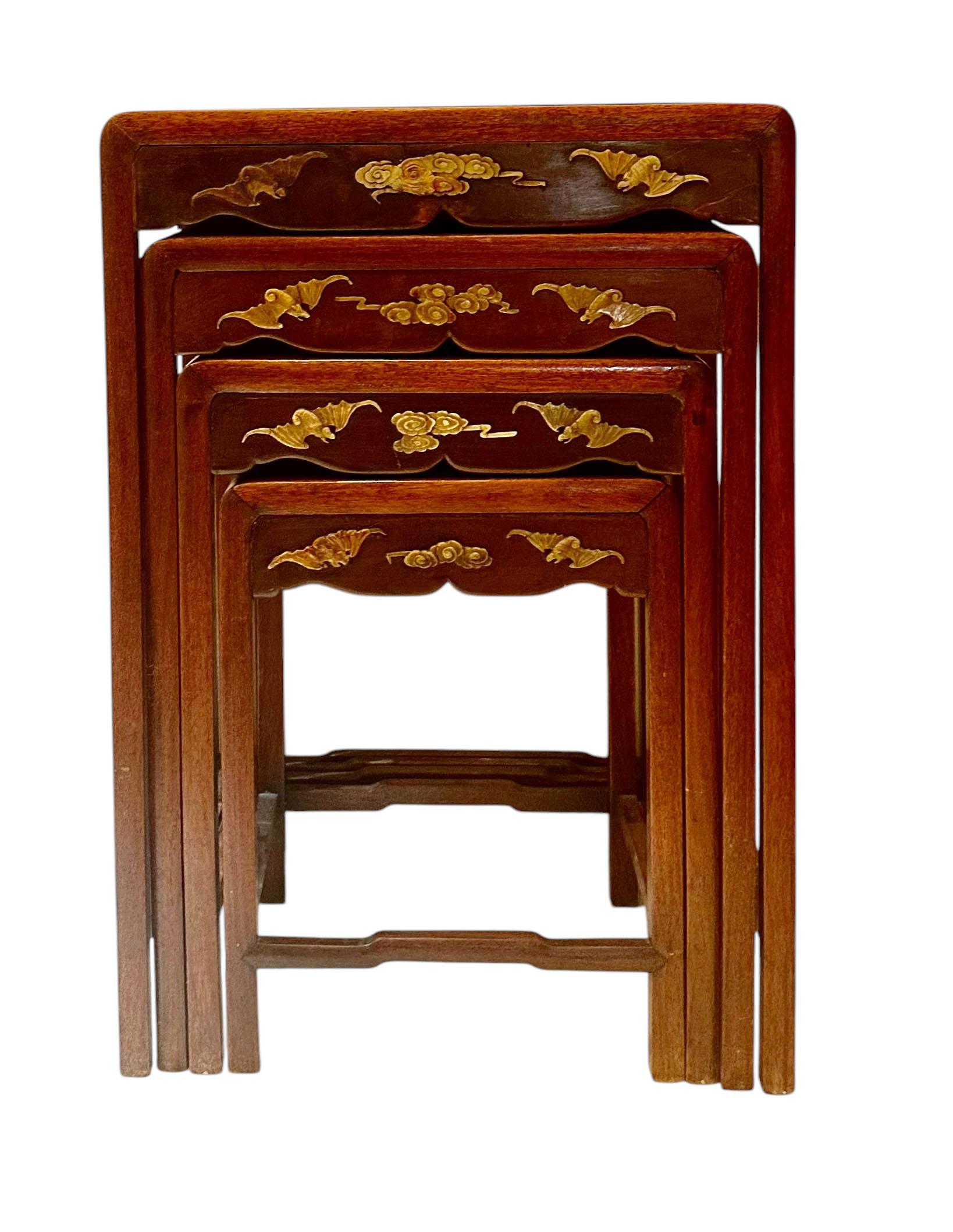 This stunning set of four Japanese nesting tables is a true work of art, skillfully embellished with intricately detailed soapstone inlays. The designs feature dragons in various forms chasing a crab amidst swirling clouds, alongside bats, delicate