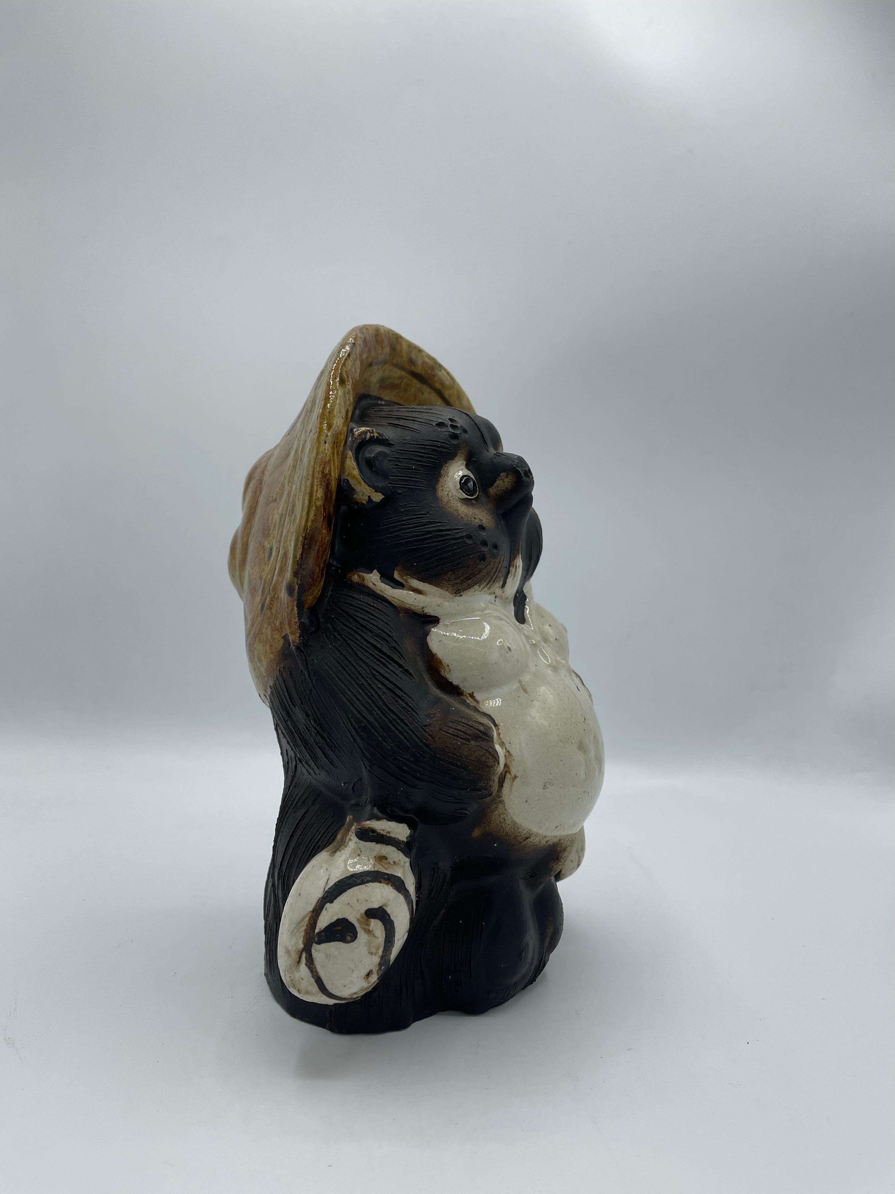 This is an object called 'Shigaraki Tanuki' which was made around 1980s.
It was made in a town called Shigaraki in Shiga prefecture in Japan.
It is made with porcelain. Tanuki is a Japanese racoon and it has 8 fortunes meanings. 

1)The Hat: The big