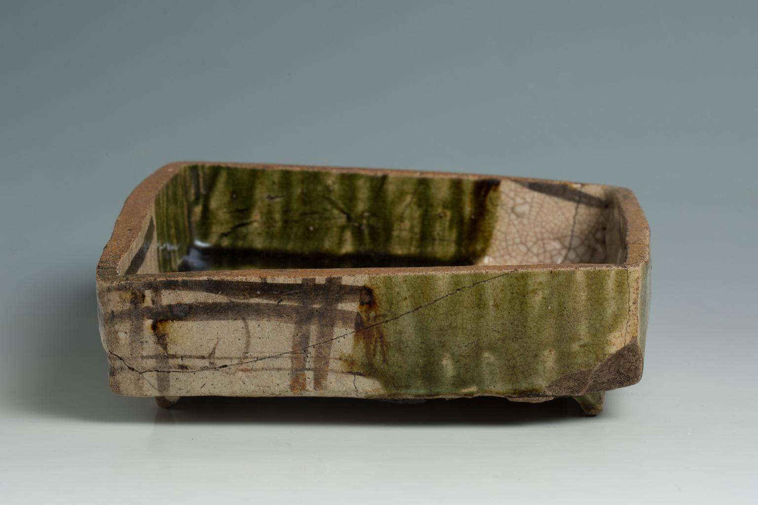 With a tactile surface texture decorated with an asymmetrical design painted between green-glazed areas, this dish is a typical example of Green Oribe (ao-oribe) ware. The glaze fired to a vivid color flows down to the side walls pooling in rich,