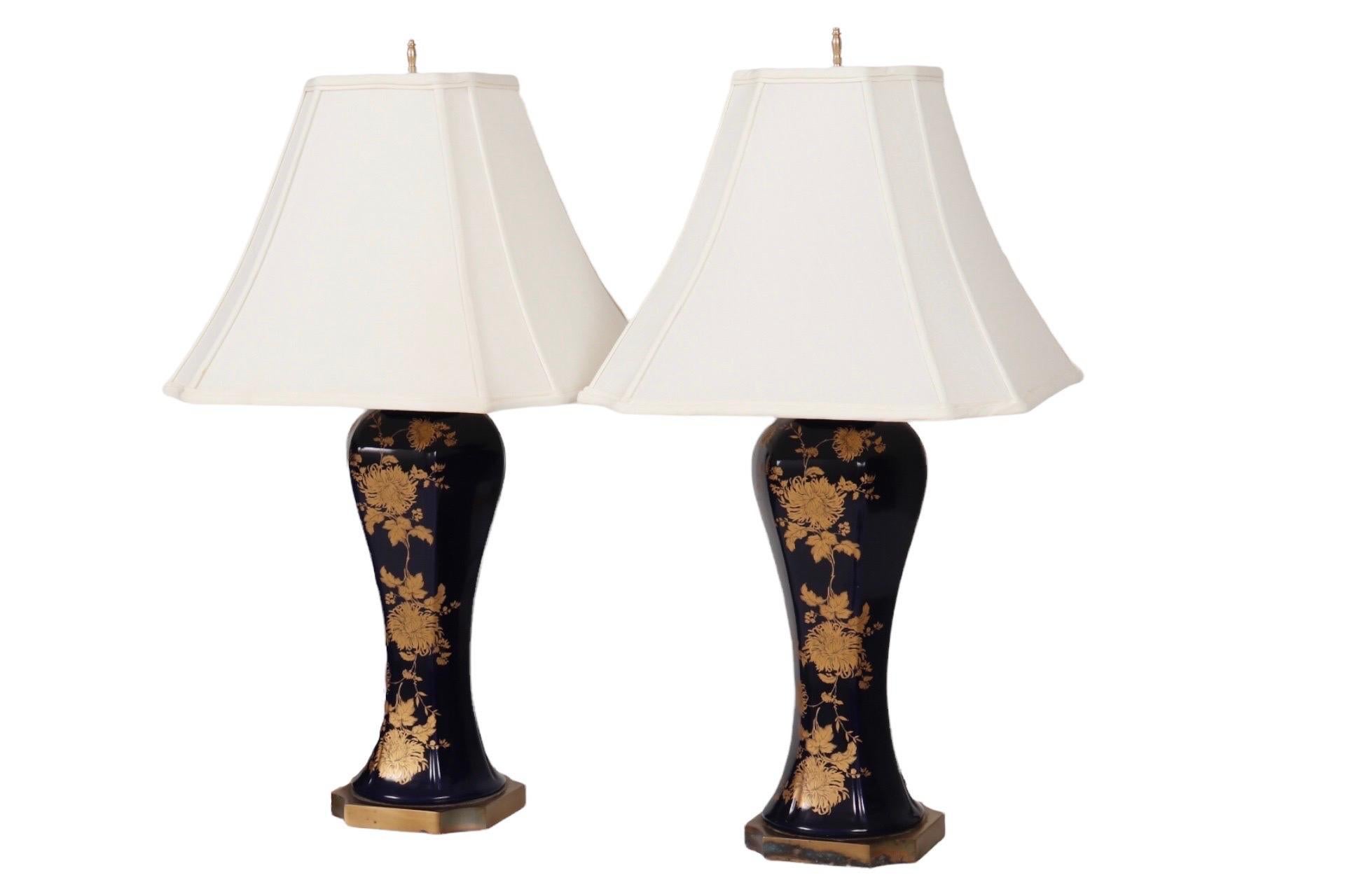 A pair of Japanese style ceramic table lamps in dark blue and gold. Urn shaped vases are exquisitely decorated with golden chrysanthemums and foliage, the oriental symbol for happiness and well being. Accompanying inverted square bell shades are