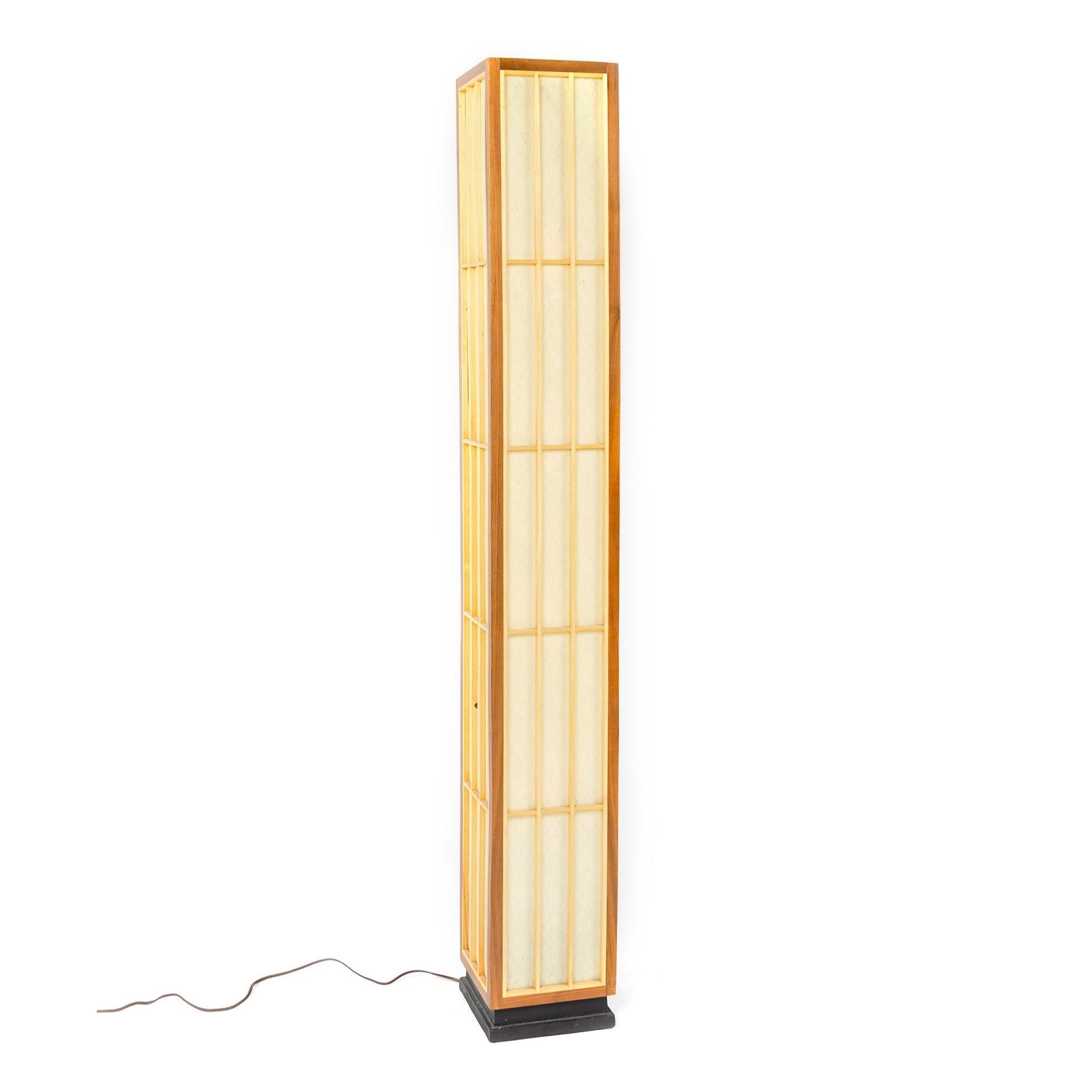 Four-sided floor lamp evoking a Japanese Shoji screen. The frame of solid walnut set on an ebonized recessed plinth base with the frame having a grid pattern of solid birch strips framing a translucent fiberglass lining which conceals four Edison