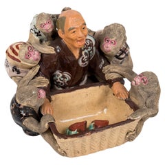 Antique Japanese Sumida-Gawa sculpture of a man distributing peaches to its monkeys