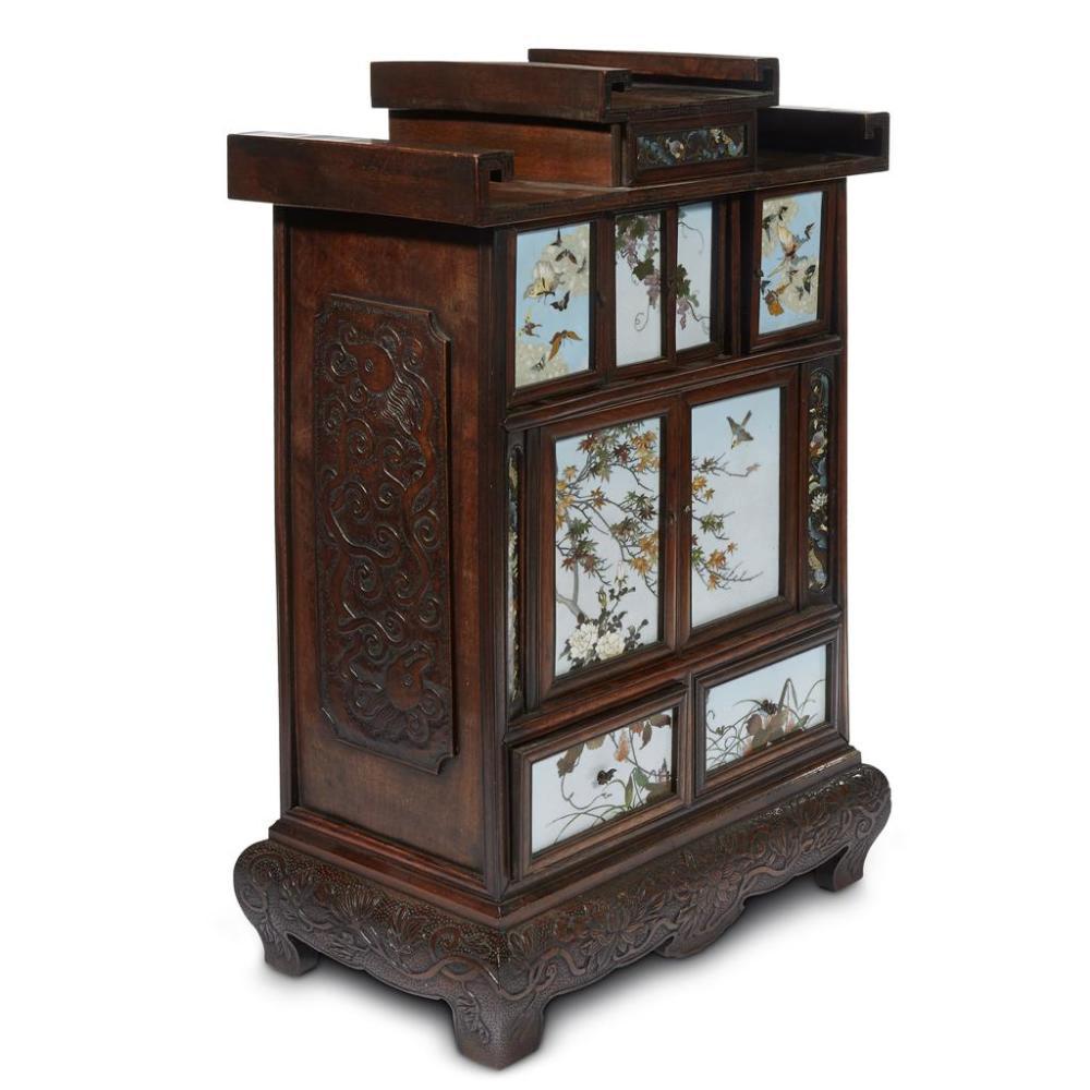 A Japanese wood and cloisonne cabinet circa Meiji period, late 19th-early 20th century. The small table top cabinet features 
a single drawer on top, four small doors with cloisonne panels on the second tier, a pair of larger cloisonne doors on the