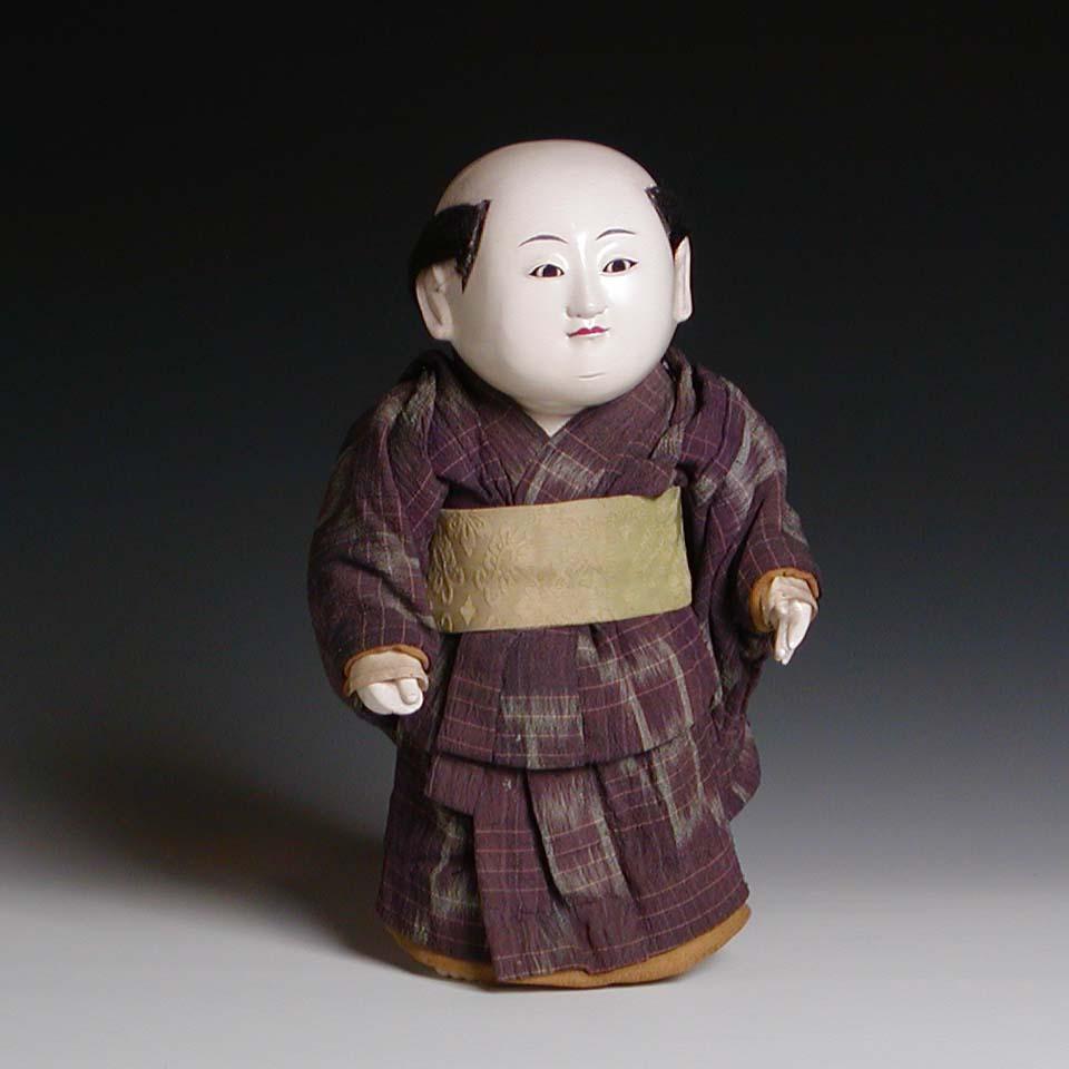 Japanese Tachiko Gosho Ningyo, standing male figure with ikat patterned purple chirimen silk kimono with tea green lining and brocade obi costume. All carved of Kiri wood (Paulownia) with fabric and wire arms, covered in multiple layers of burnished
