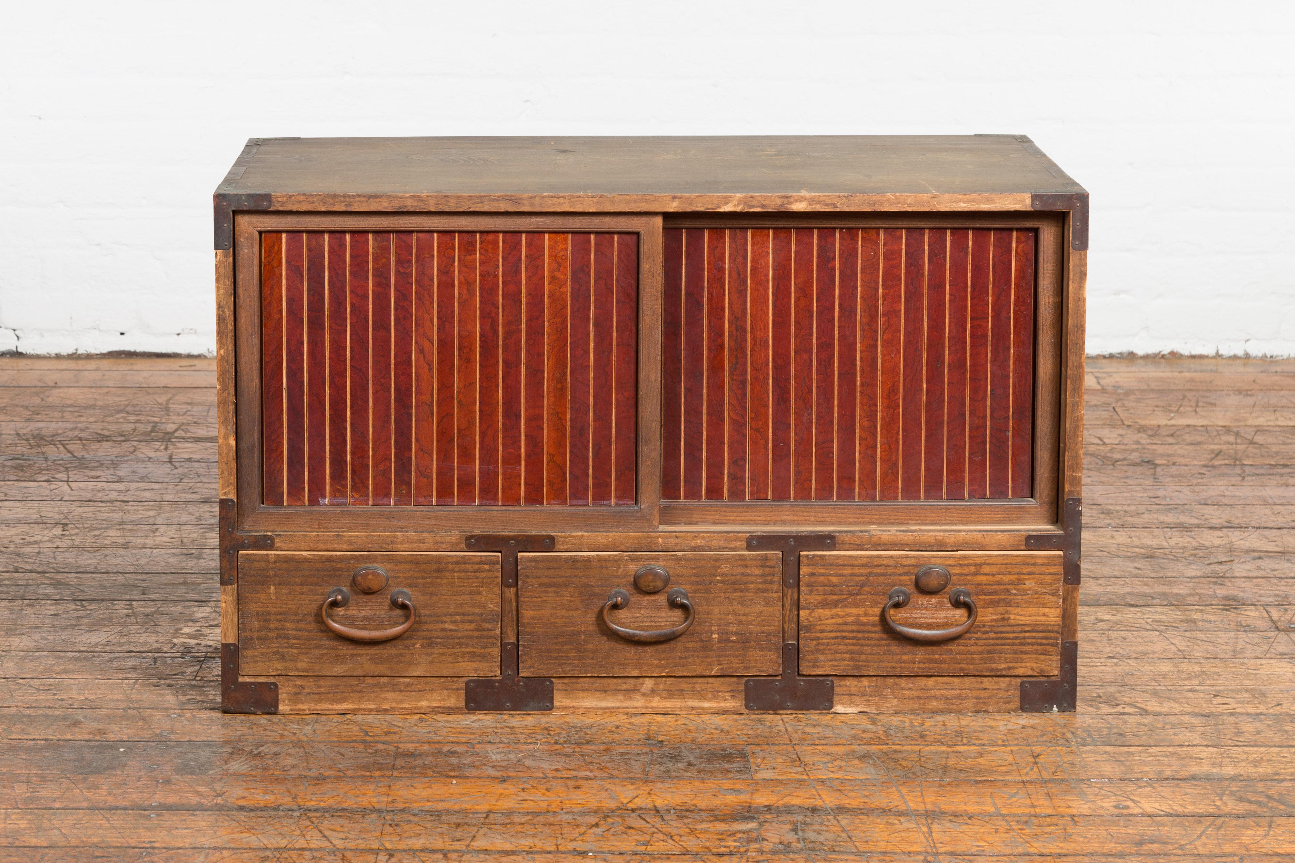 A Japanese Taisho period kiri wood two toned kitchen low storage cabinet from the early 20th century, with sliding doors, drawers and removable panel. Created in Japan during the Taisho period running from 1912 to 1926, this kiri wood low cabinet