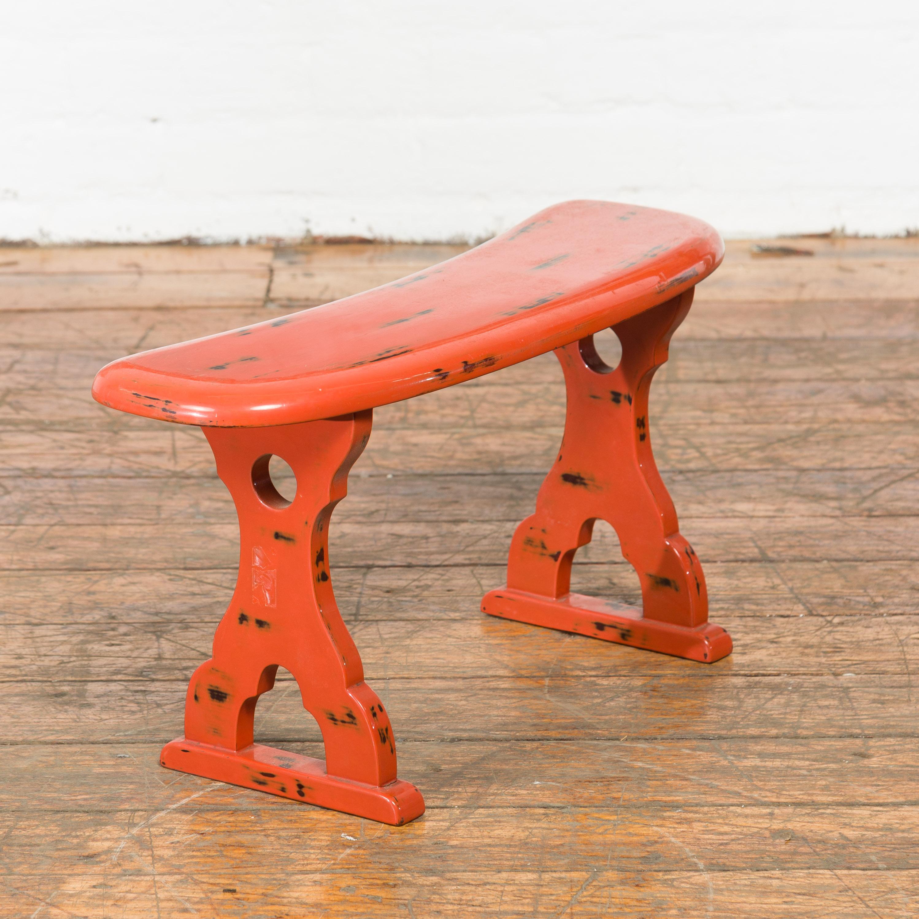 A Japanese Taisho period negora lacquer arm stool from the early 20th century, with cinnabar color. Created to be used on an opium bed, this Japanese Taisho period stool features a slightly curving top supported by two X-Form legs pierced with
