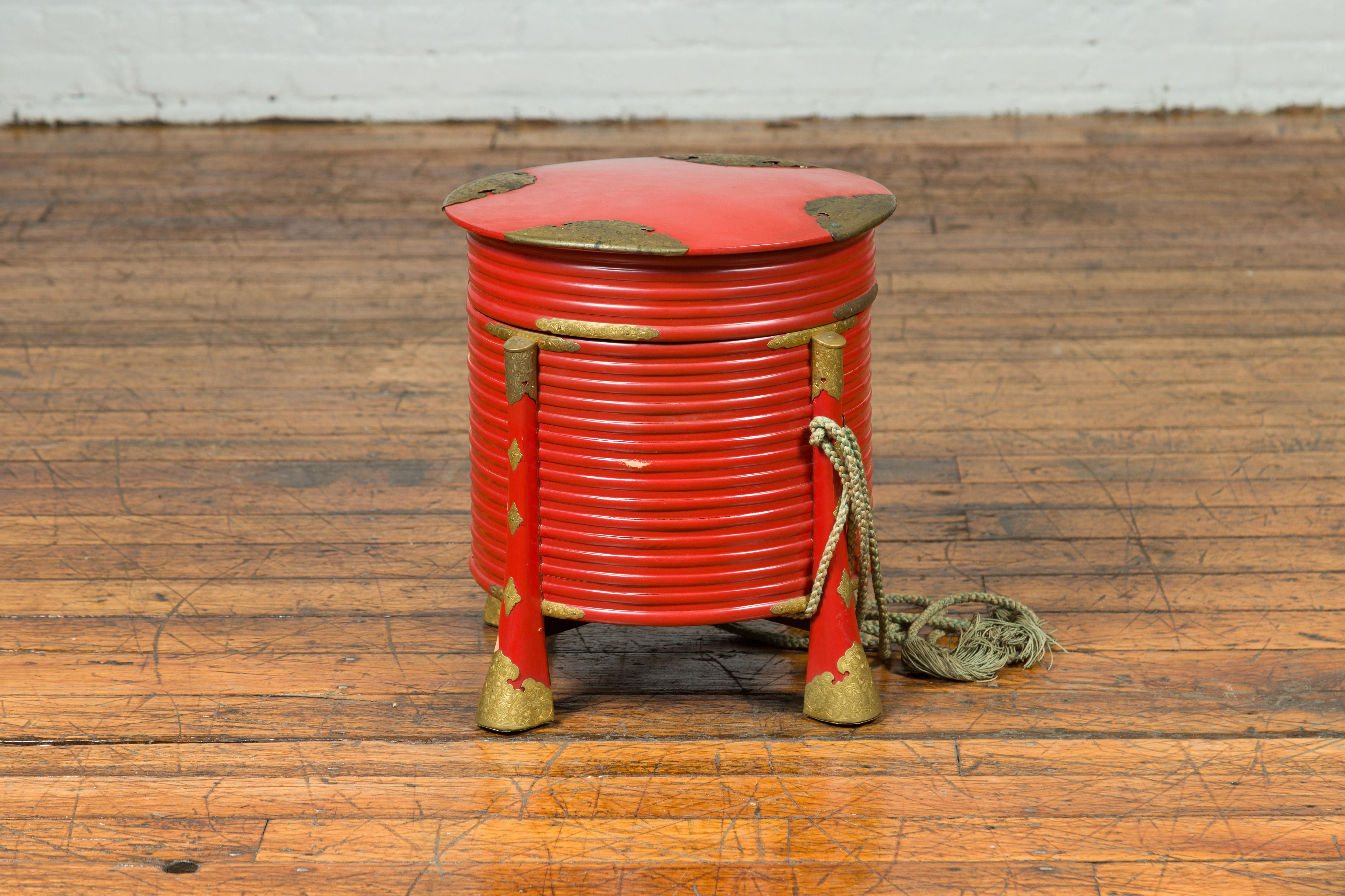 A Japanese Taisho period Hokai box from the early 20th century, with red lacquer, ornate brass accents and original rope. This vibrant Japanese Taisho period Hokai box, crafted in the early 20th century, exudes both historical charm and functional