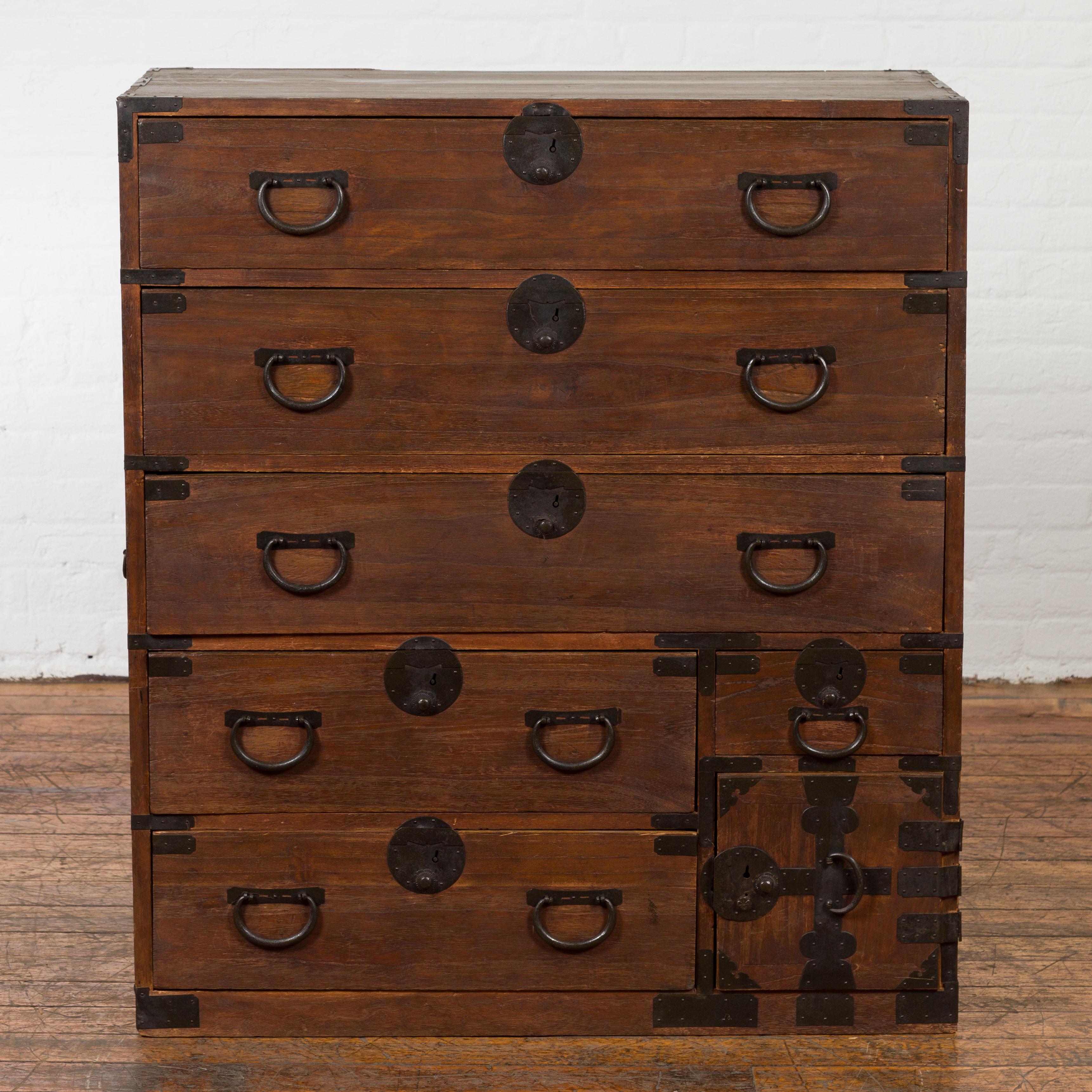 A Japanese Taisho period single section tansu clothing chest from the early 20th century in Isho-dansu style, with six drawers, safe, carrying handles and dark patina. Created in Japan during the Taisho period in the early years of the 20th century,