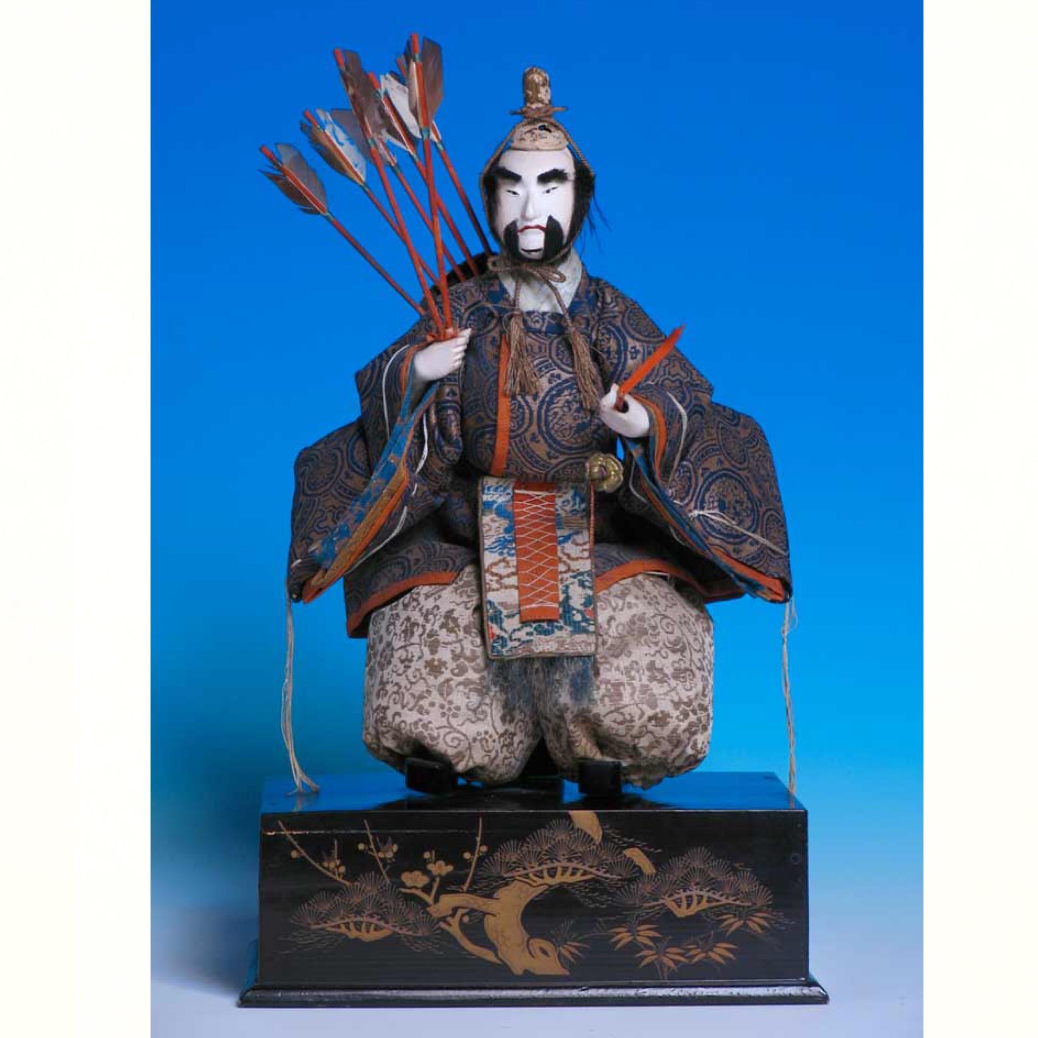 Japanese Takeda Hina Ningyo, of a pair of seated ministers for the Girl’s day display, each costumed in matching brocades characteristics the house of Takeda, supported on lacquered and gold painted box bases, each with swords, arrows and bow, the