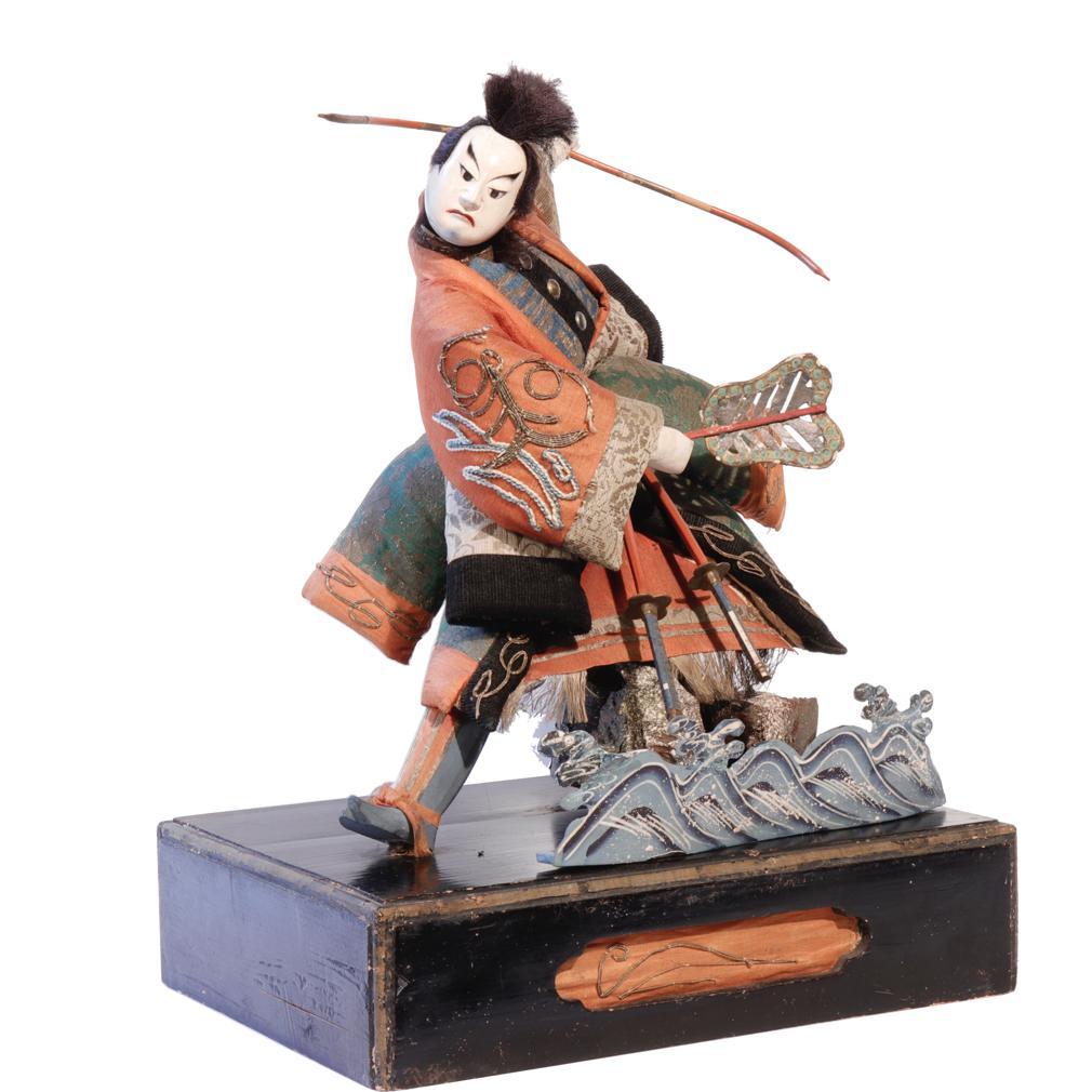 Takeda Ningyo giapponese che raffigura un attore di un'opera Kabuki nel ruolo di un guerriero in mare con il disegno dell'ancora ricamato sulla manica e le onde di scena in primo piano. Il costume è realizzato in seta chirimen, velluto birodo e