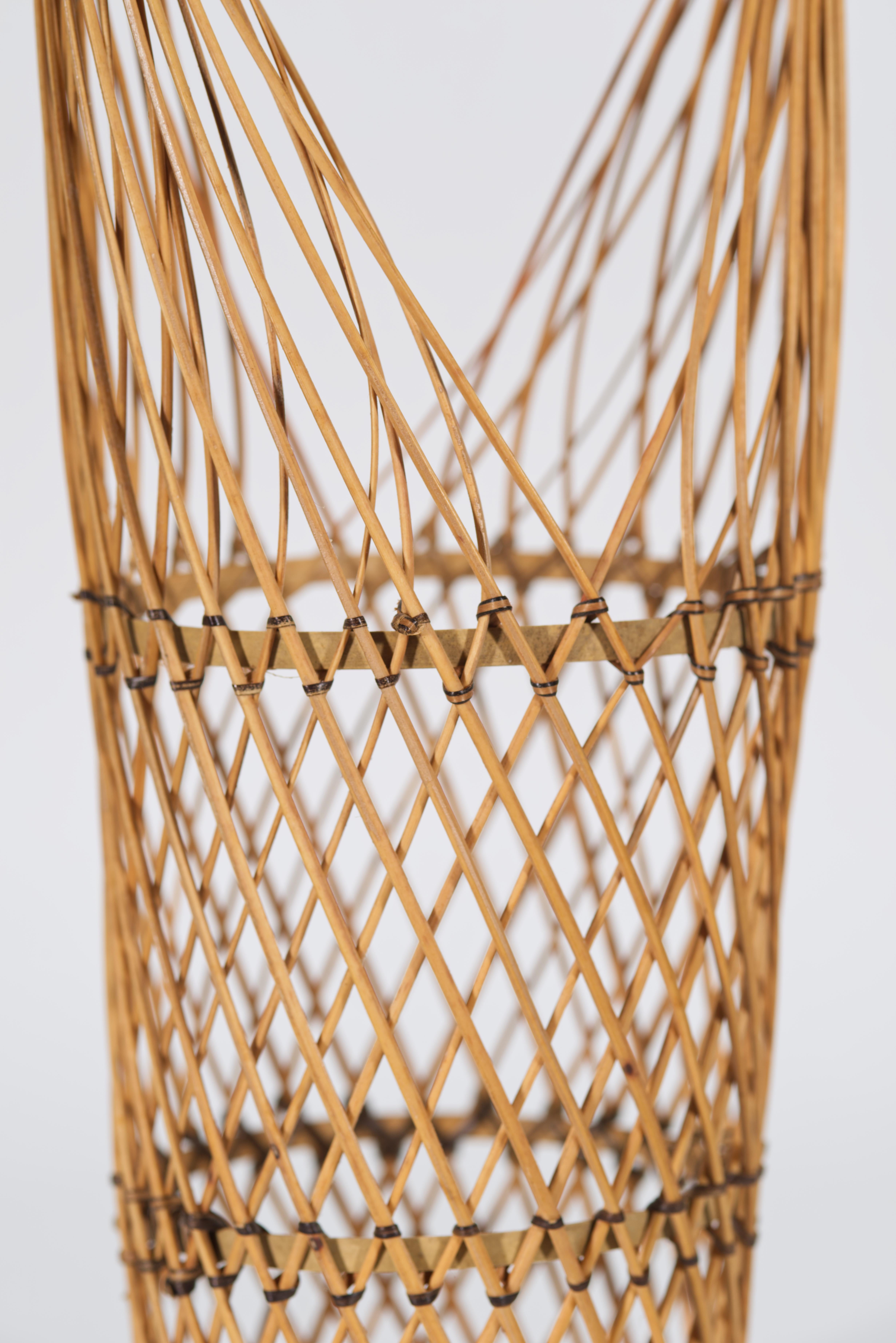  Vintage bamboo Ikebana basket features tall cylindrical shape with prominent rounded handle. The basket is woven of thin round bamboo strips that are secured with burned or tinted bamboo fibers, adding stability and durability to a light, ethereal