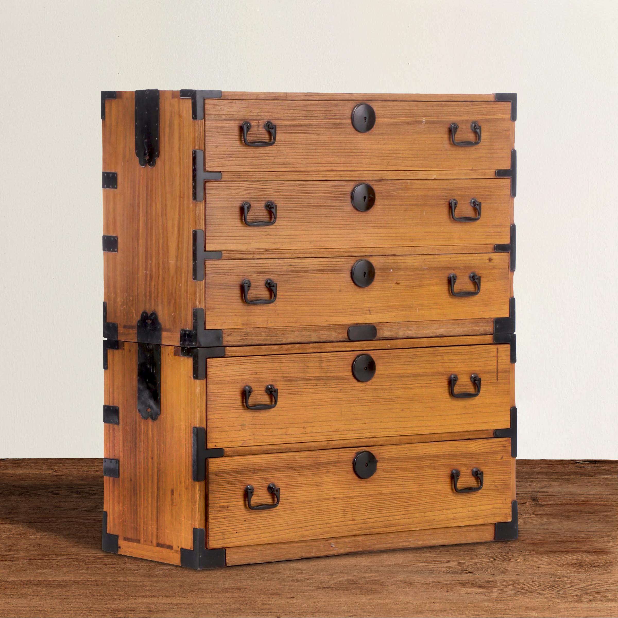 A gorgeous mid-20th century Japanese pine tansu stacked chest with five drawers total, and black iron hardware. Separated, the chests contain three drawers and two drawers each, and are the ideal bedside tables or nightstands.