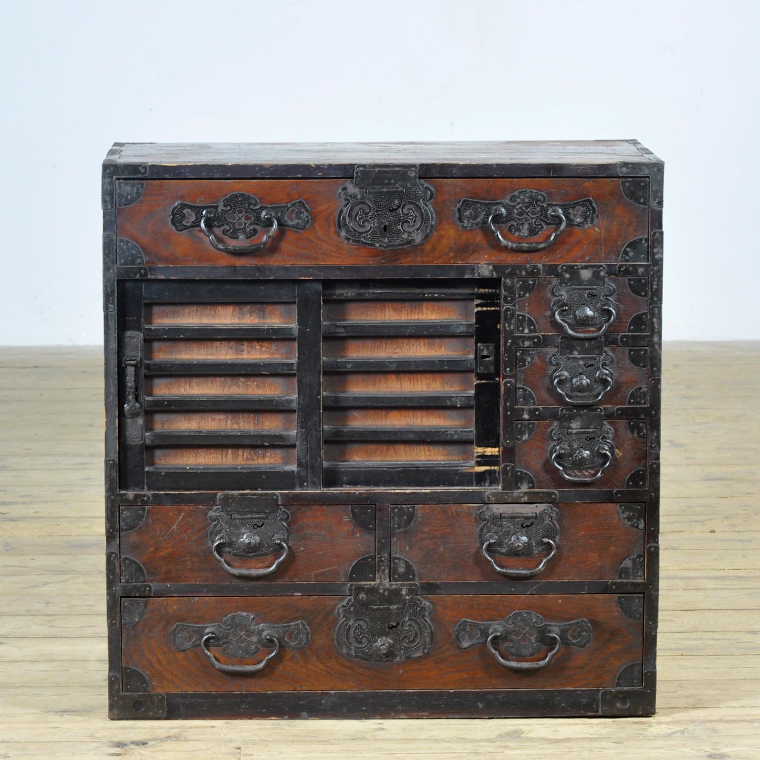 Traditional Japanese Tansu chest of drawers from the 1890s. Made during the late Meiji era (1868-1912), this piece exudes authenticity and character. It has a warm, timeworn look that has stood the test of time. The robust wrought iron hardware with