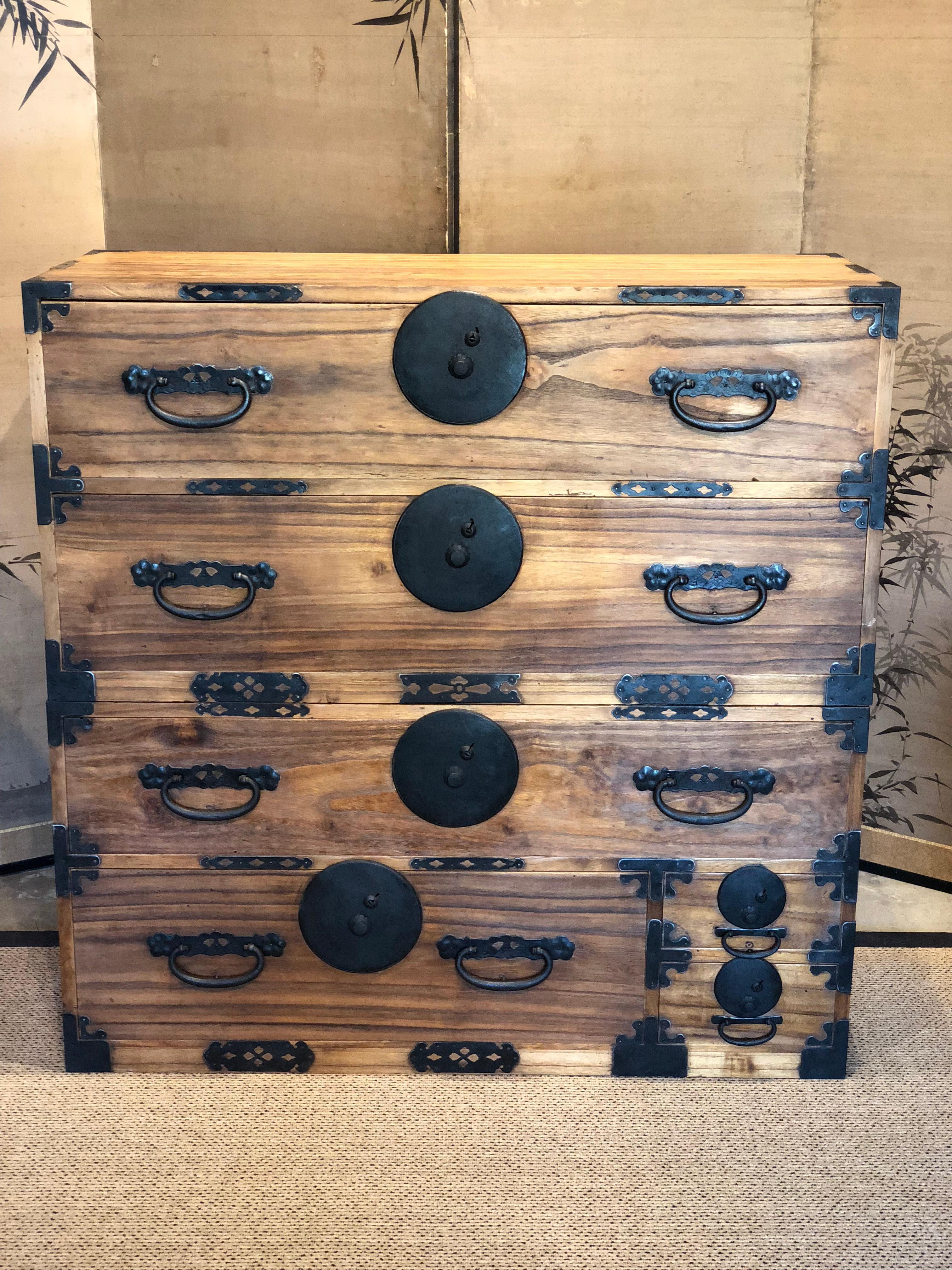 Japanese Tansu chest constructed of kiri with large iron handles and massive iron lock plates with a distinctive motif. Elongate escutcheon are gracefully fitted behind each handle. Heavy metal strapping hinges protect and reinforce the safe door.