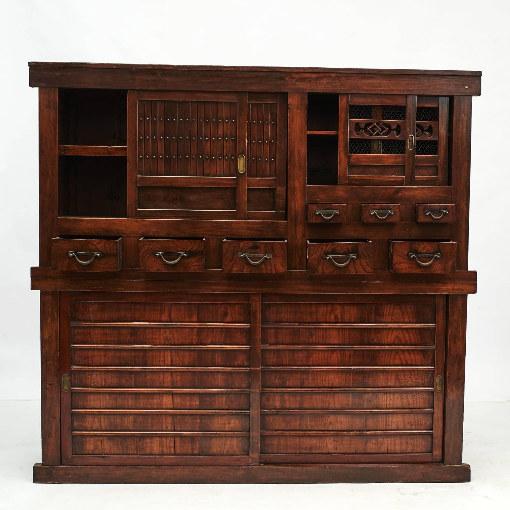 A Japanese Meiji period two-section tansu cabinet (also known as Mizuya Dansu) crafted in pine and elm burl.
The top section consist of sliding doors and drawers in elm wood. Lower section with pair of sliding doors. Within the sliding doors are