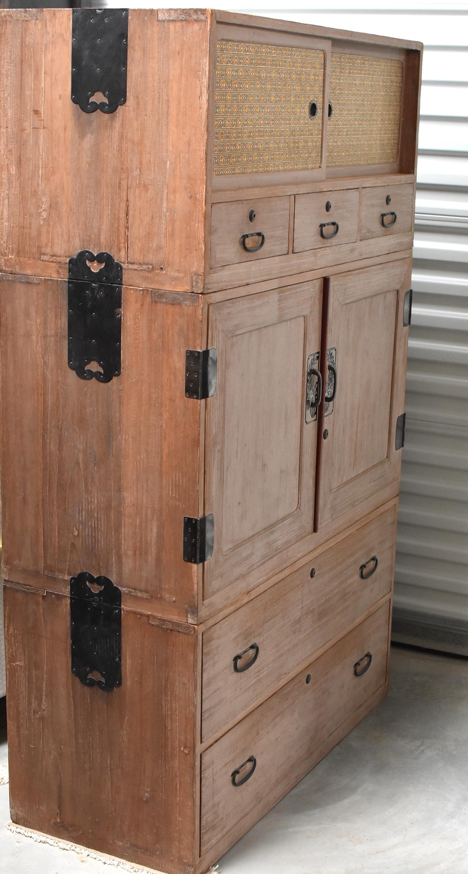 This beautiful Tansu is made of three separate chests. The top has a pair of sliding doors behind which hide a shelf and 2 drawers. There are also three exterior drawers. The middle section is a wonderful 3-tray system which offers great storage for
