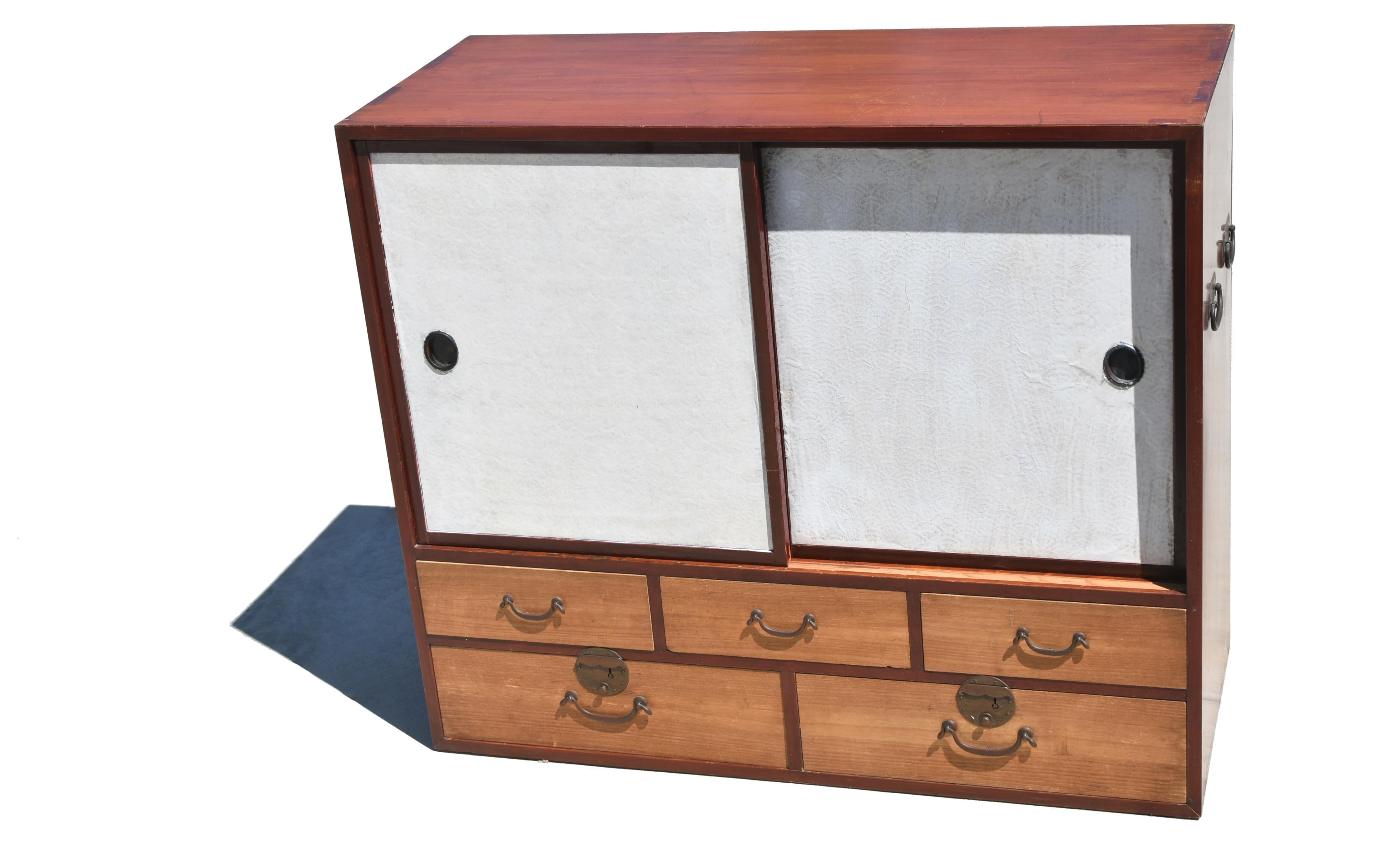 A most charming Tansu. The sliding doors are covered in white Japanese hand made rice paper in traditional shell pattern and fitted with oval bronze hardware. Behind the doors a large chamber equipped with a removable interior shelf supported by
