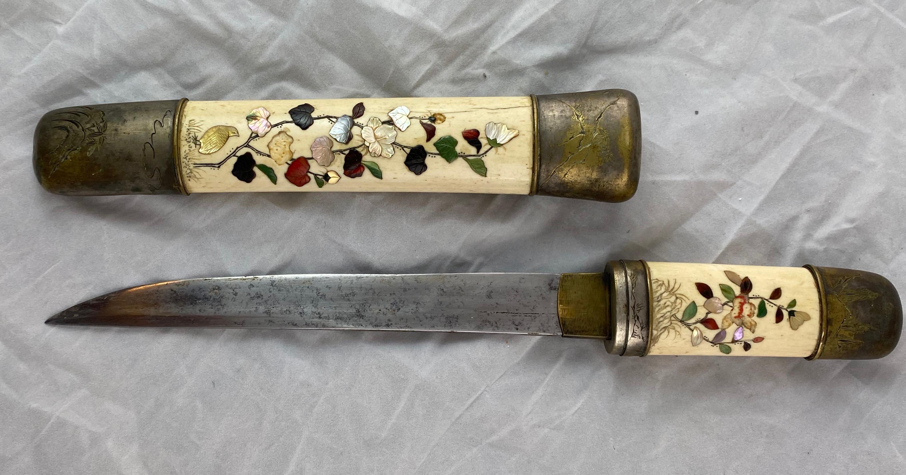 A nicely designed Japanese Tanto with a bone scabbard that has inlays of stones and mother of pearl. Motives of flowers and birds.