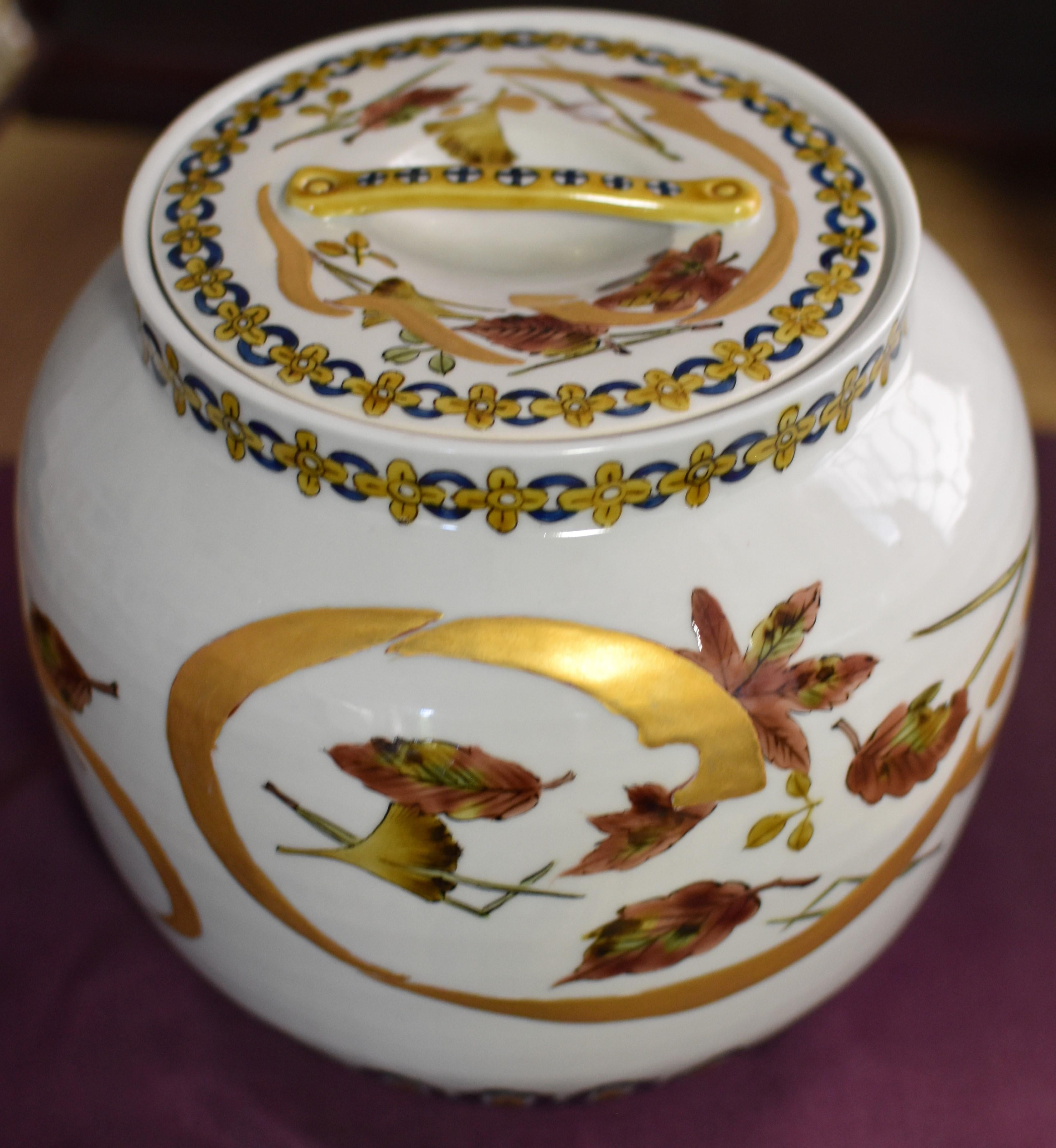 Exquisite Japanese signed and hand painted porcelain mizusashi/Water Jar features an attractive automn scene in warm orange and yellow on a white background and two intricate pattern in yellow and deep blue decorating the rim and base. Gold accents