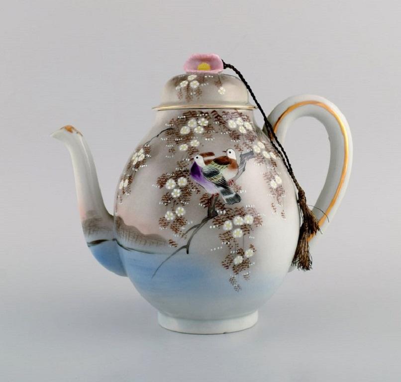 Servicio de té japonés en porcelana pintada a mano. Mediados del siglo XX.
Consta de dos tazas de té con platillos, una tetera y cinco platos.
La taza de té mide 10 x 5 cm.
Diámetro del platillo: 14.5 cm.
La tetera mide 22 x 19,5 cm.
Diámetro